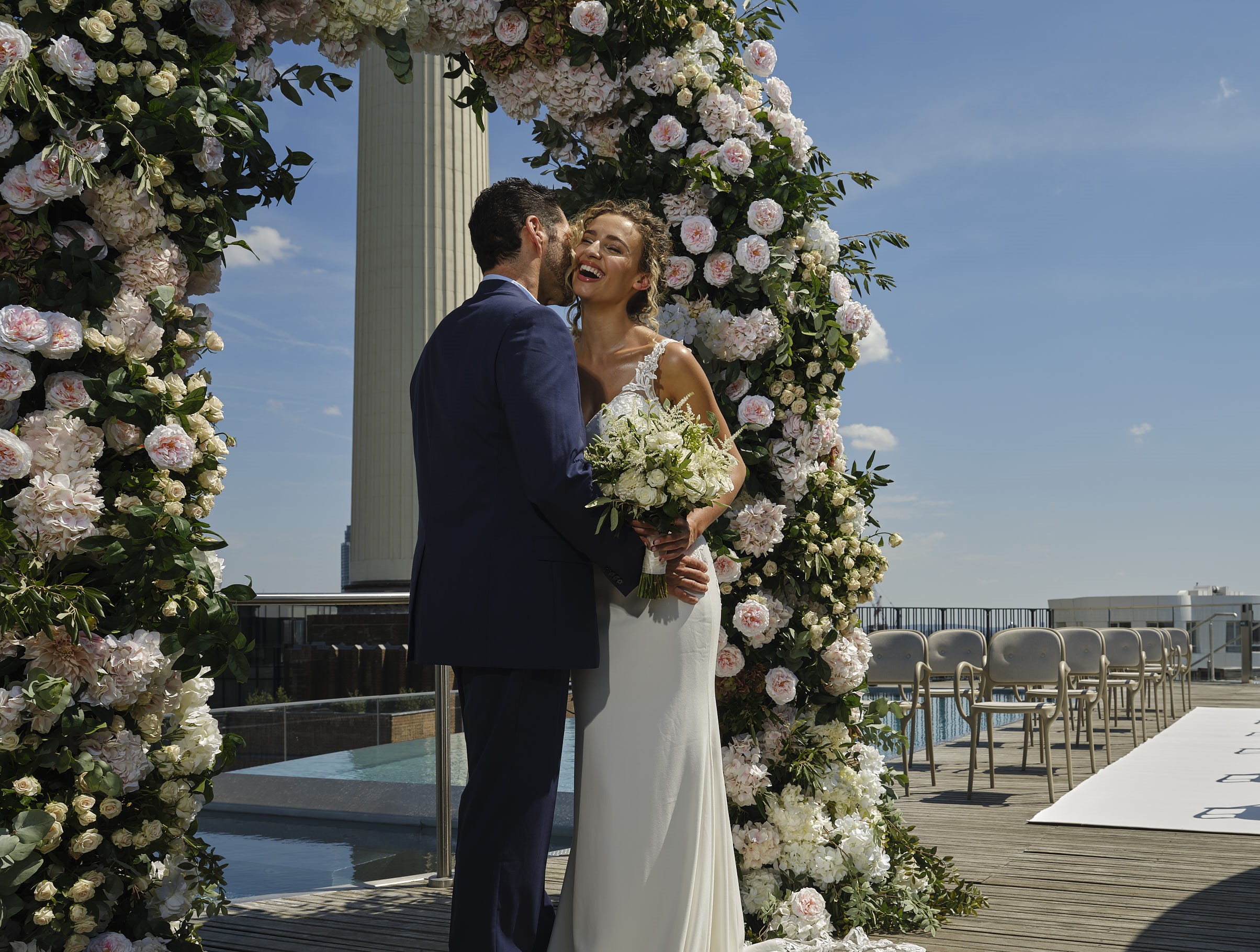 Outdoor wedding ceremony at art'otel London with floral arch and skyline backdrop.
