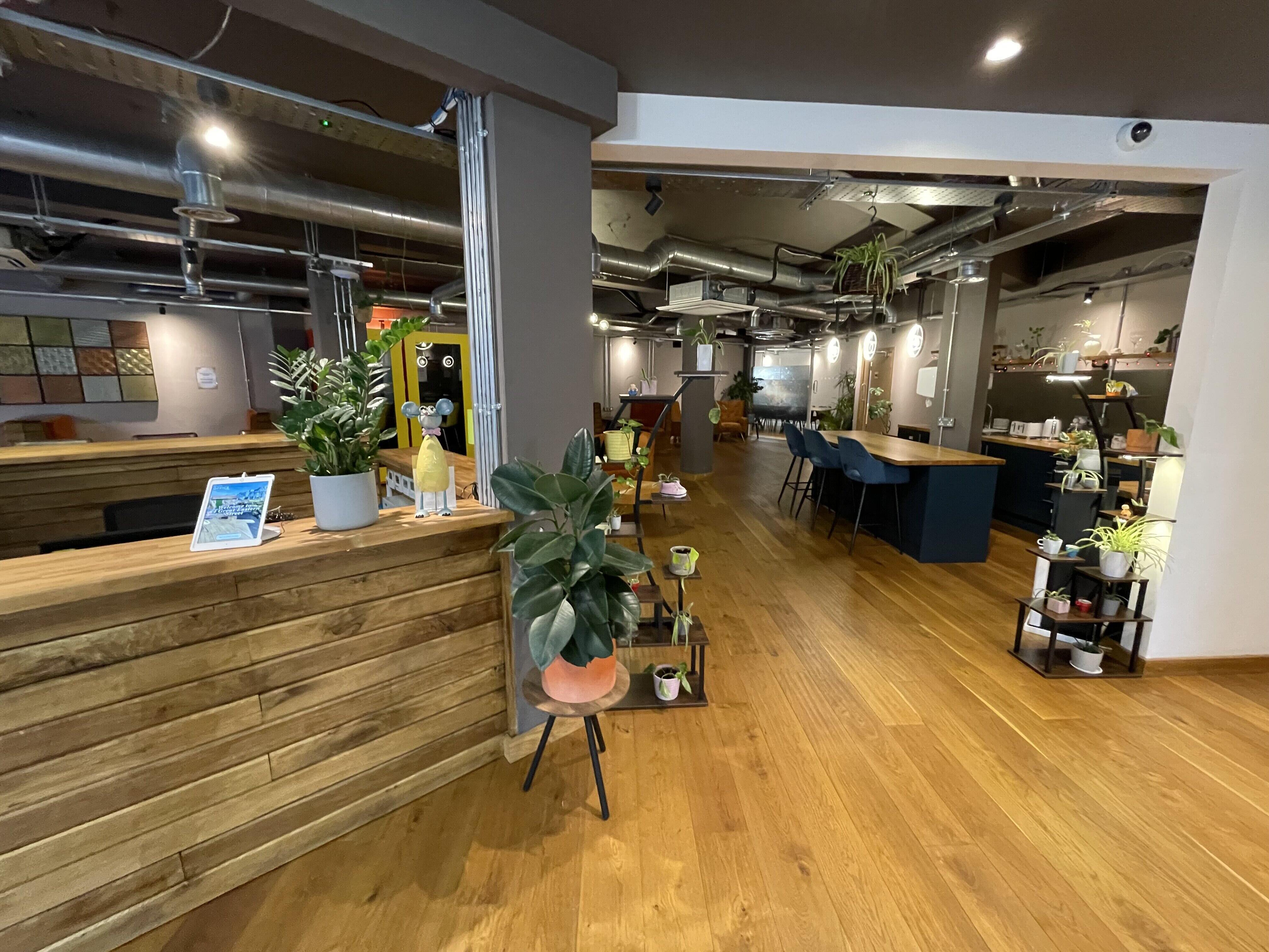 Industrial breakout space with bar seating and greenery for networking and co-working events.