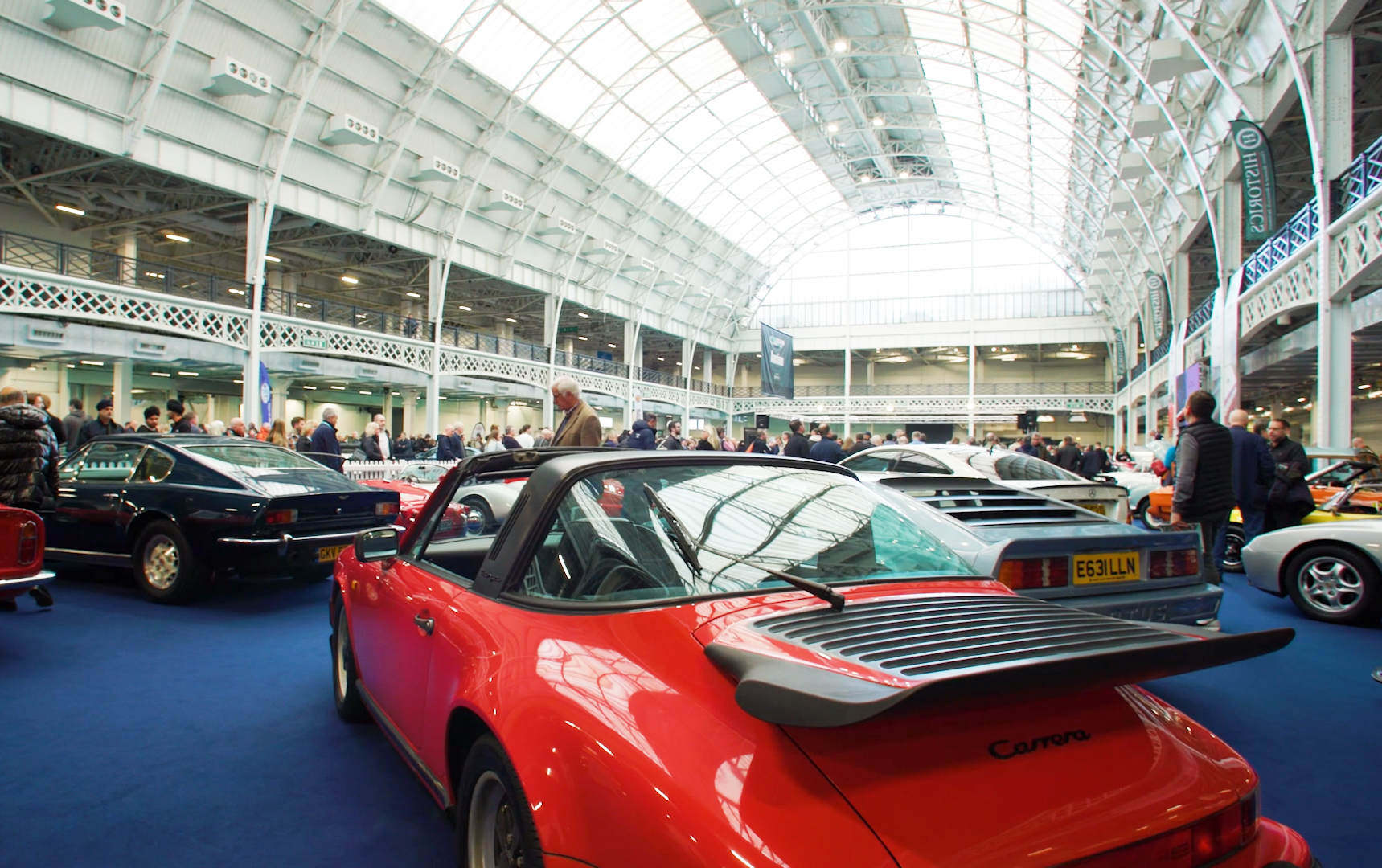 Automotive exhibition at The National Hall, Olympia with spacious layout and diverse vehicles.