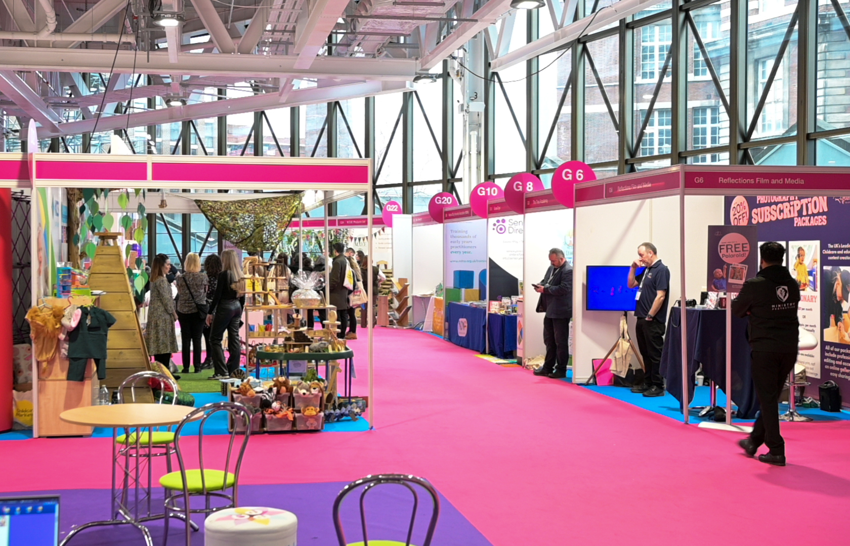 Vibrant exhibition space in West Hall, Olympia with colorful booths for events and networking.