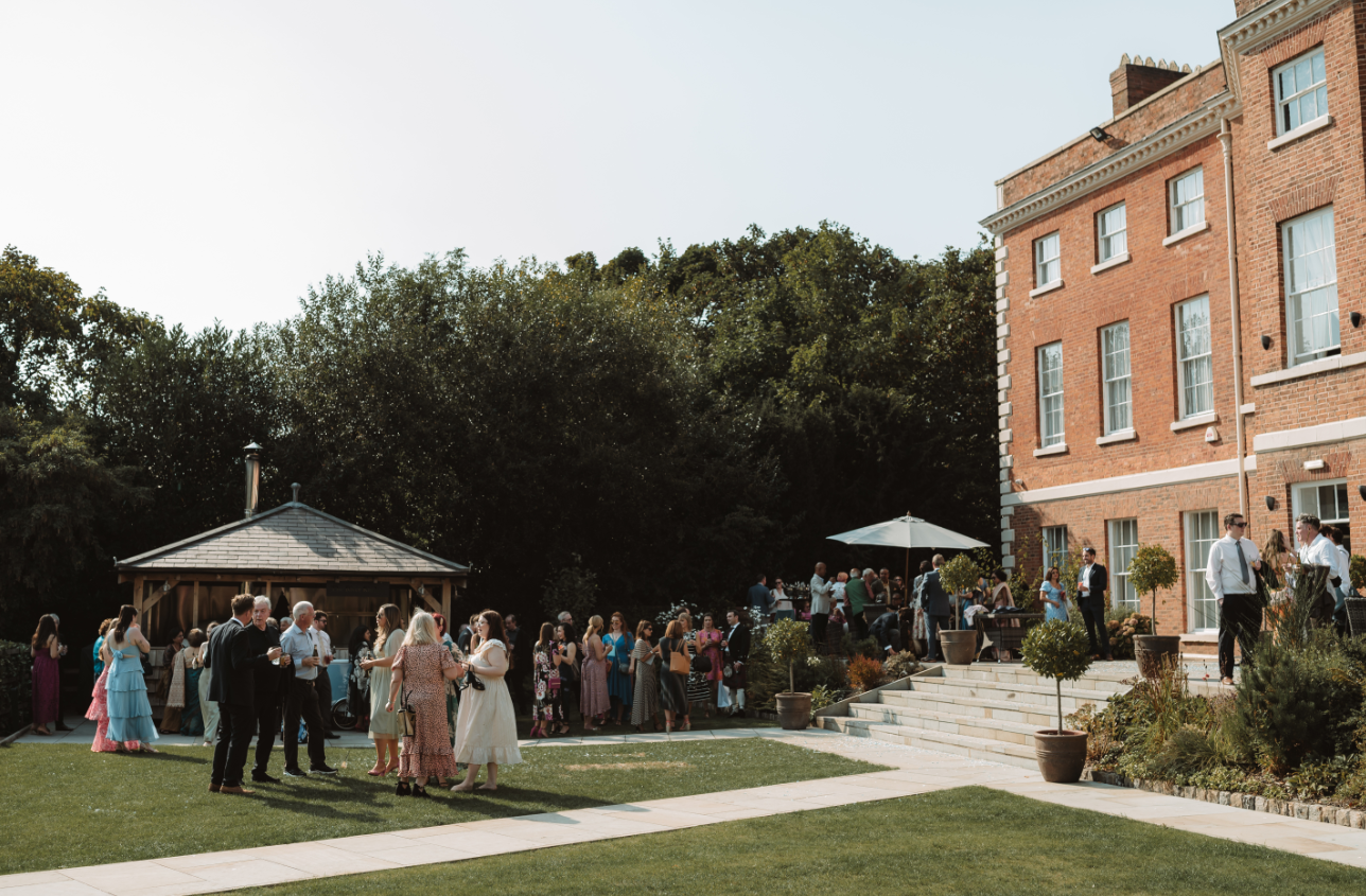 Outdoor summer party at Old Palace Chester with lush greenery and elegant architecture.