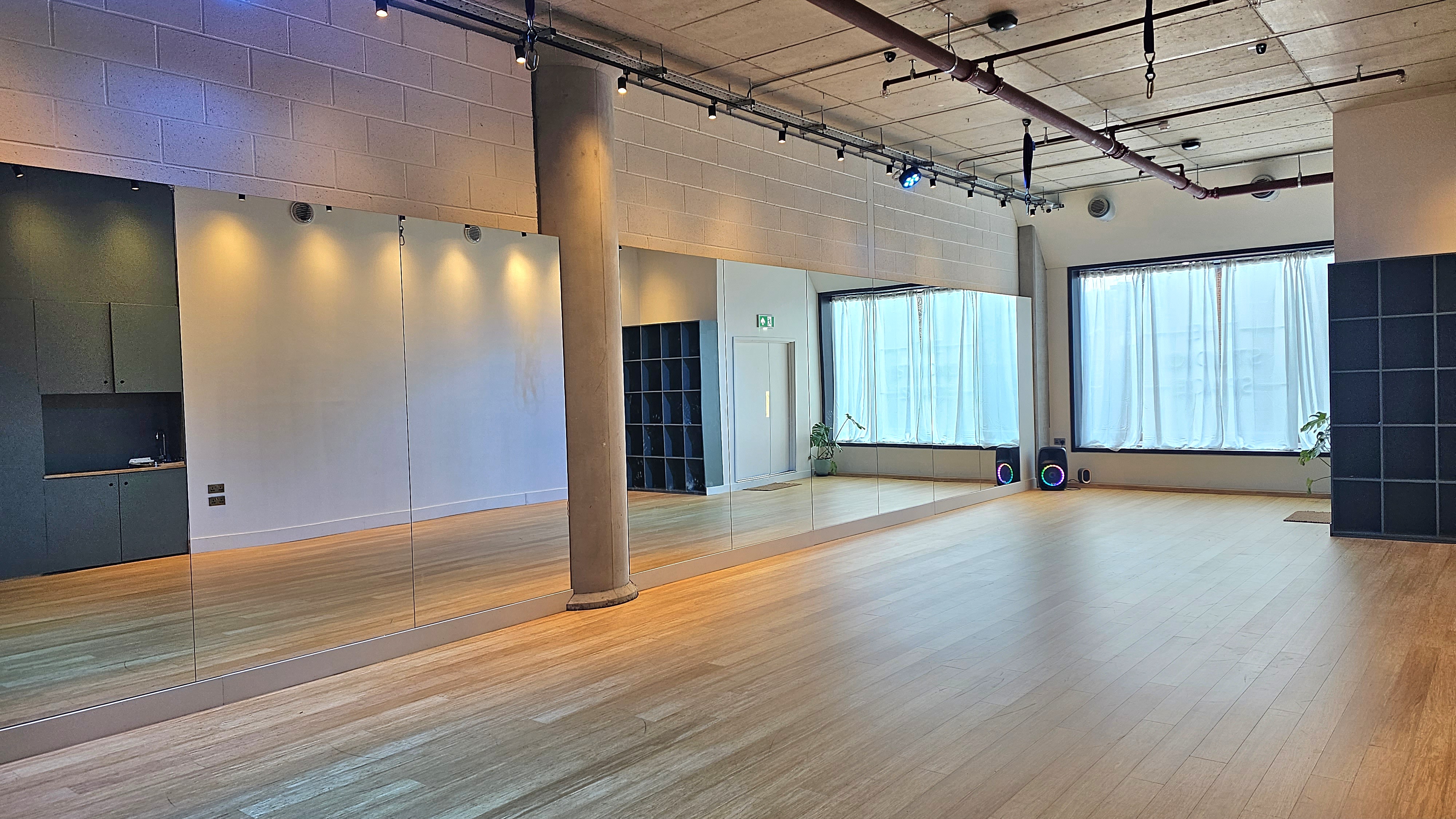 Versatile event space with natural light and polished floors, perfect for workshops and fitness classes.
