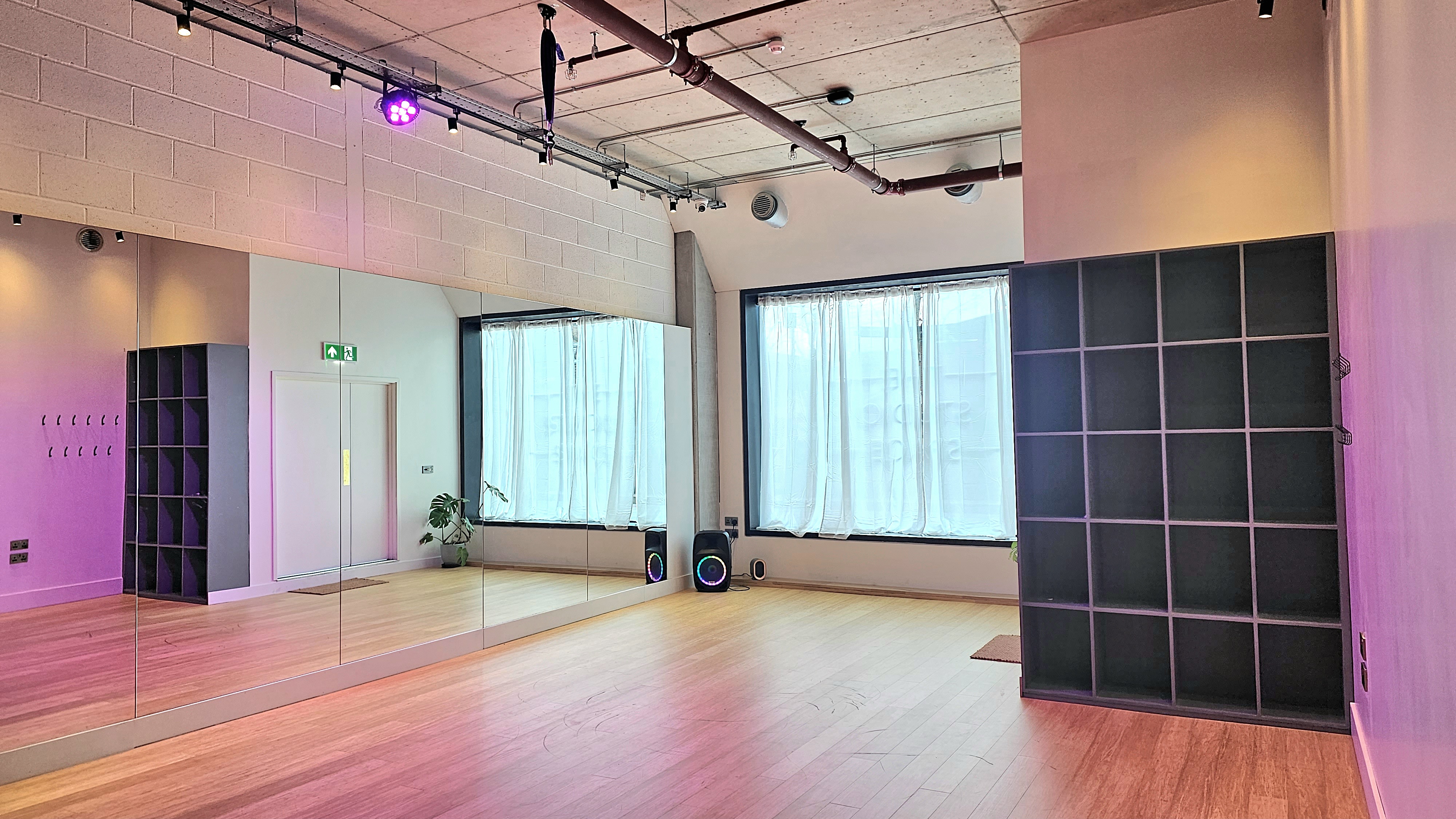 Versatile event space with natural light and mirrored wall for workshops or gatherings.
