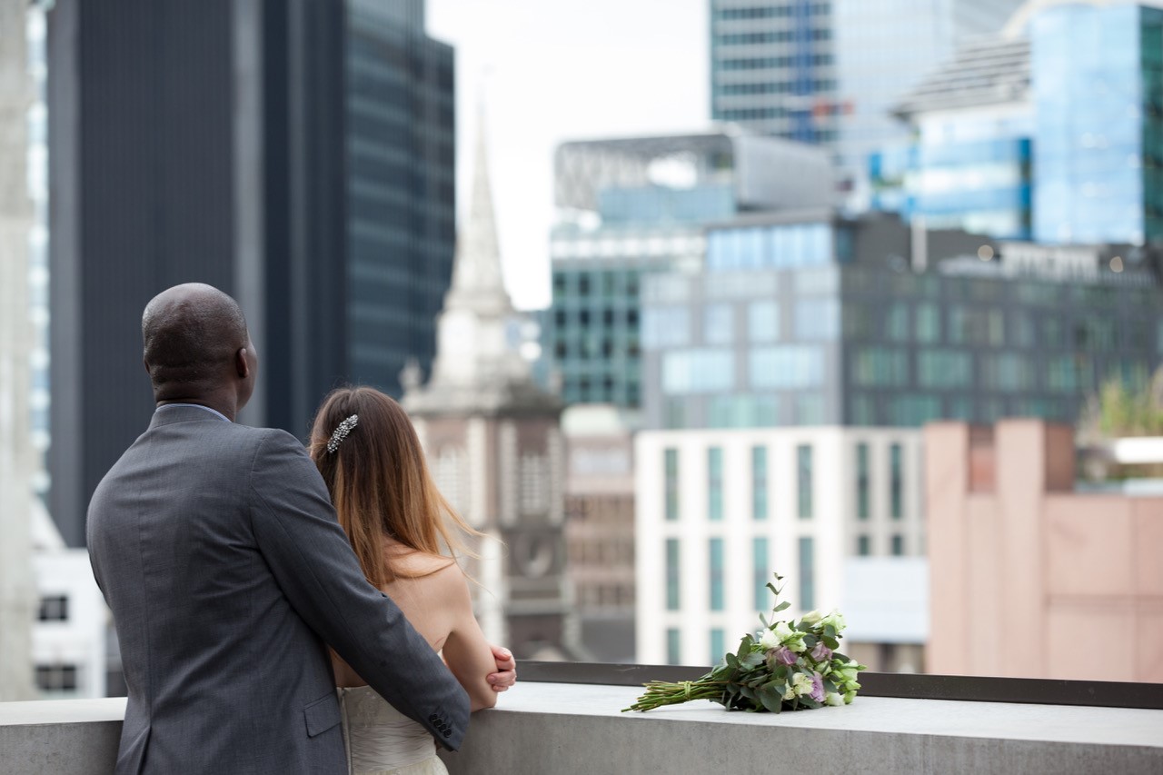 Couple enjoying a rooftop summer party with city skyline, perfect for weddings and events.