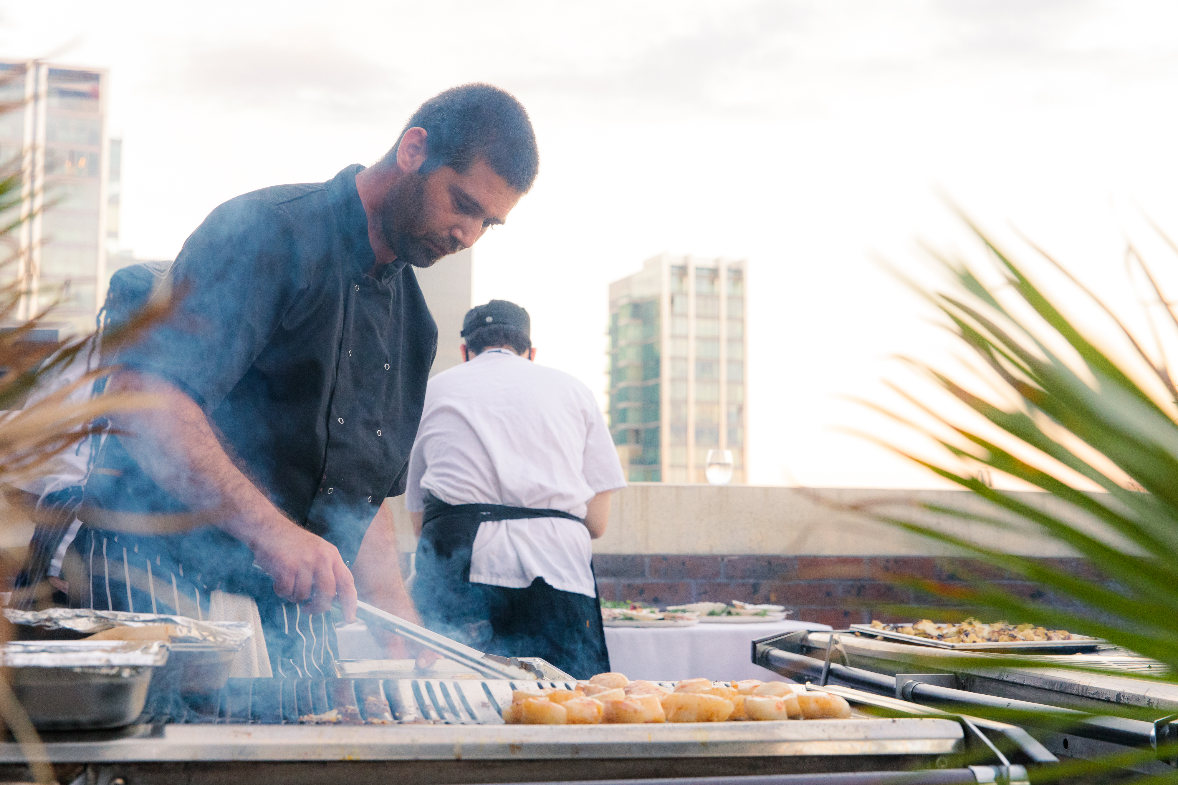 Chef grilling at Summer Party Rooftop event, showcasing quality catering and socializing.