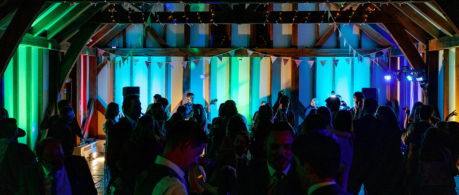 Vibrant Christmas party at Brookfield Barn with colorful lighting and a lively band.
