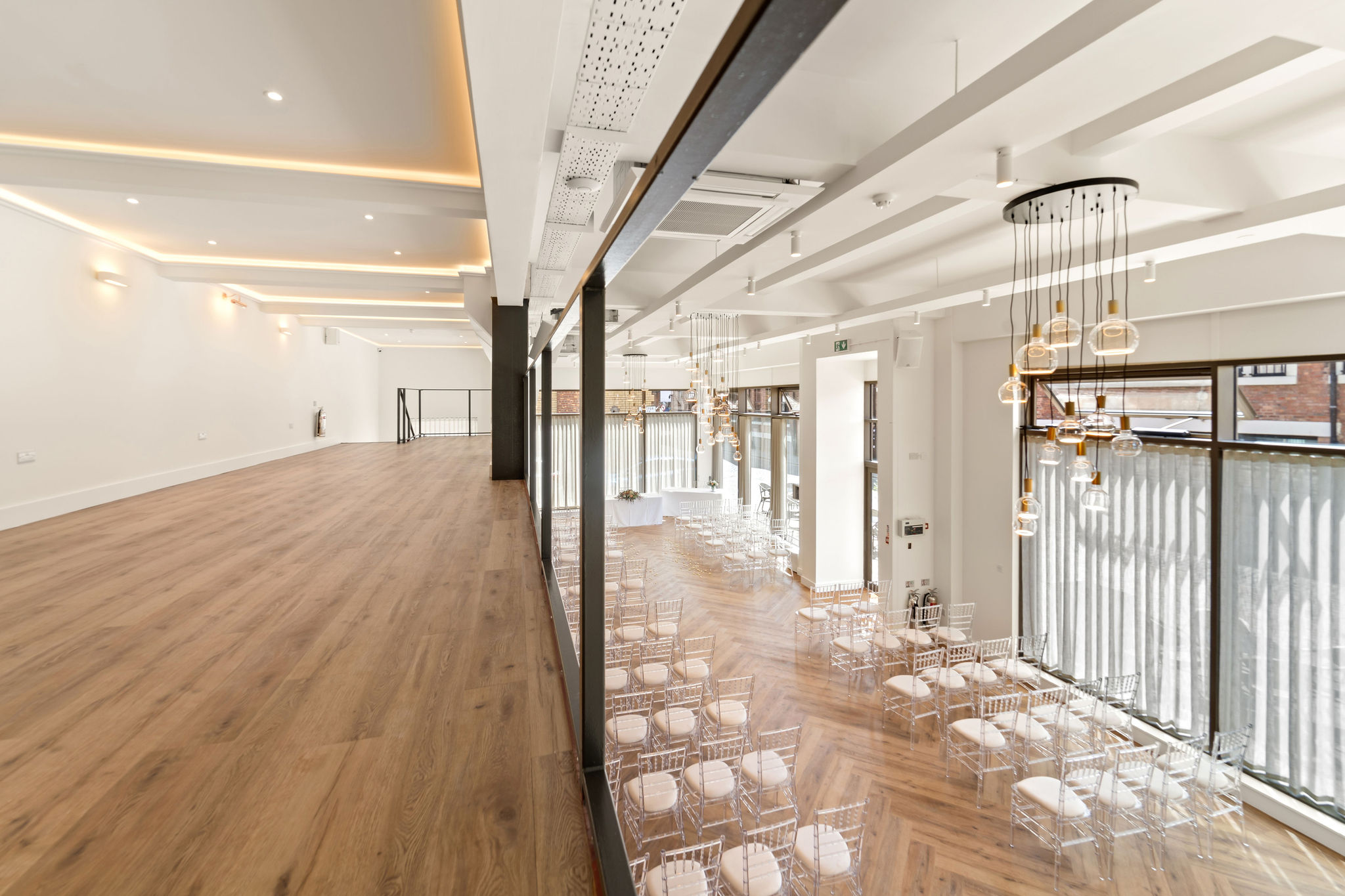 Minimalist dual-level event space with wood floors for upscale networking and ceremonies.