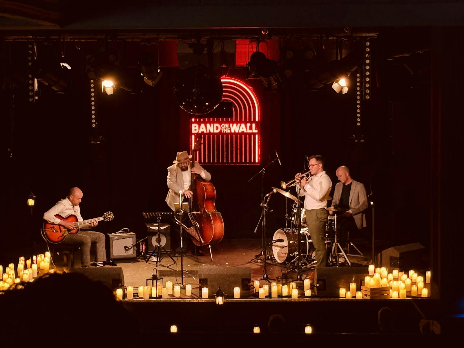 Band on the Wall venue with neon backdrop and candles for corporate events.