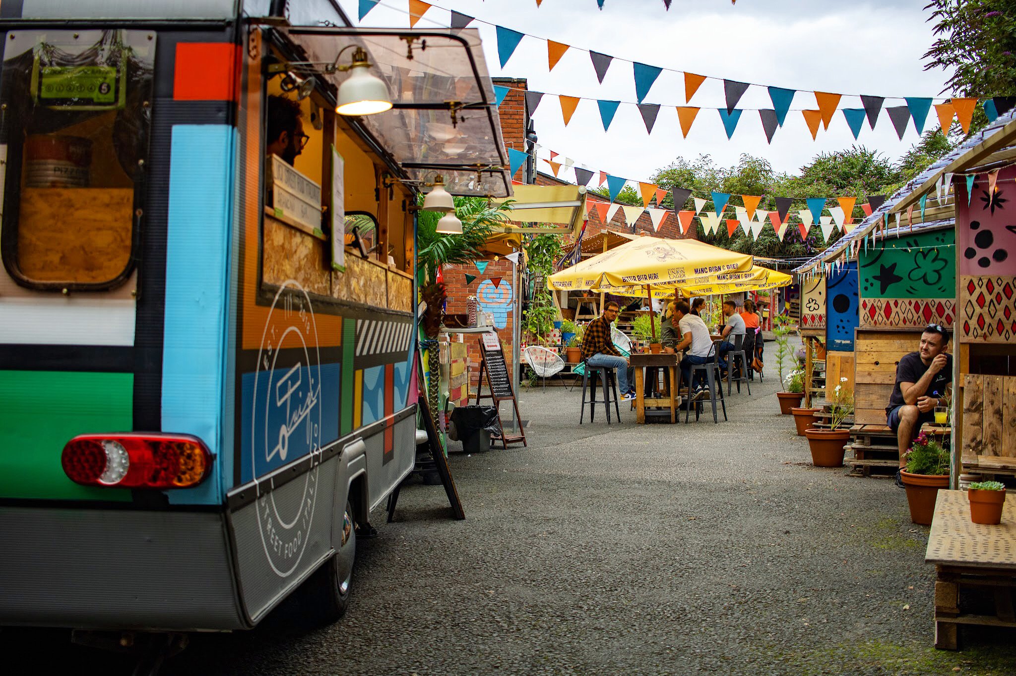 Vibrant outdoor event space at GRUB MCR with food trucks and communal seating.