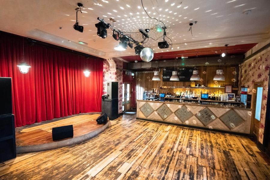 Versatile event space at The Deaf Institute with stage, bar, and ambient lighting.