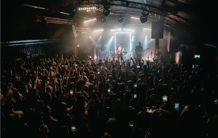 Gorilla live music event with vibrant lighting and excited crowd raising hands.