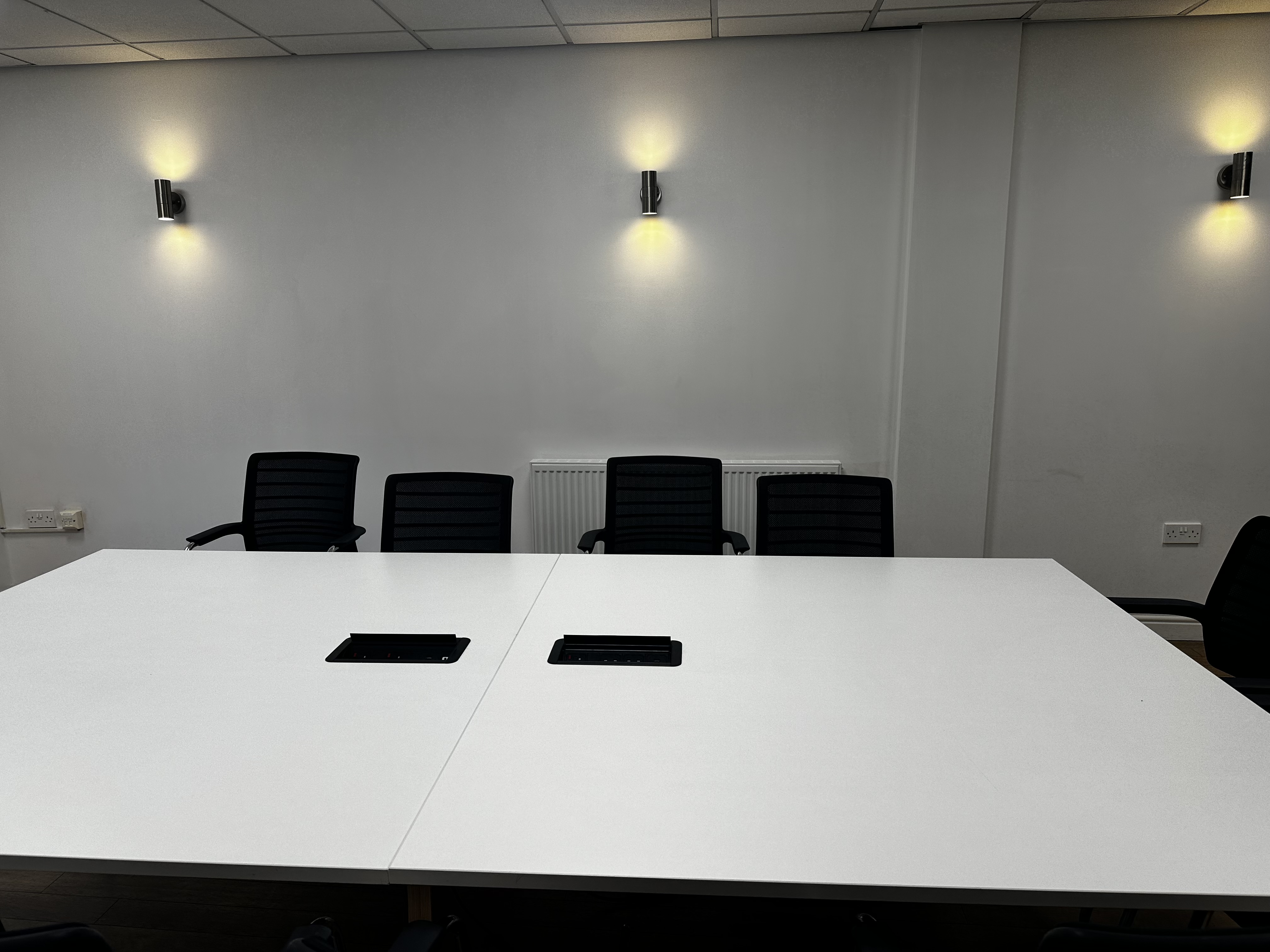 Modern executive suite conference room with white table, ideal for presentations and meetings.