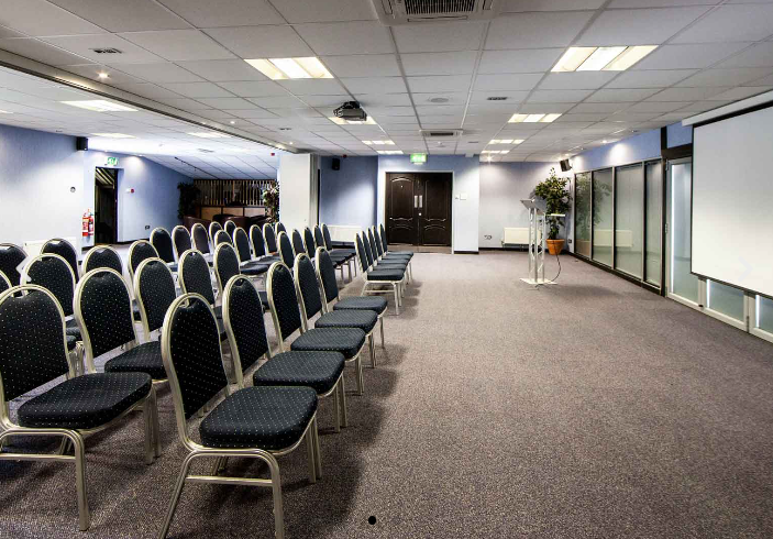 Chestnut suite theater-style meeting room with podium and projection screen for corporate events.