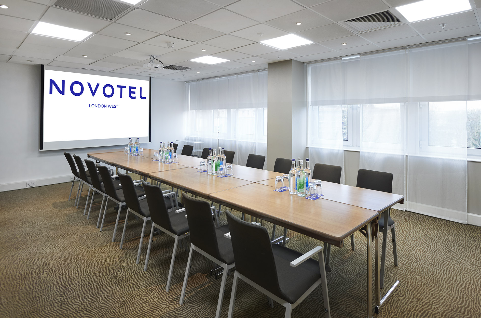 Modern meeting room at Novotel London West for corporate events with projection screen.
