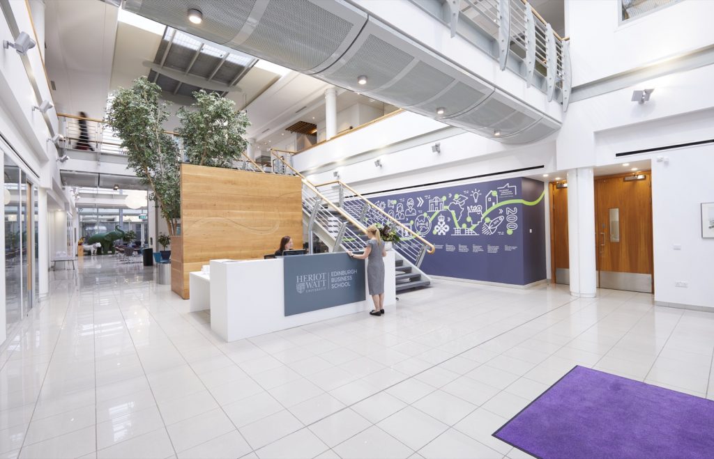 Cairn Auditorium: Modern atrium event space with branding wall for conference registration.