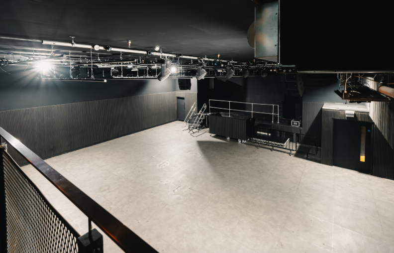 Spacious modern event venue with exposed lighting for corporate meetings and creative events.