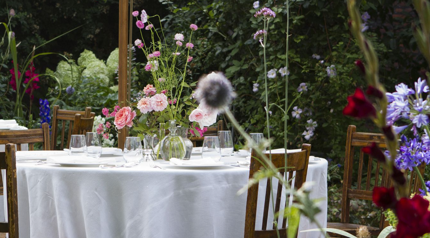 Elegant outdoor dining table with floral arrangements in The Norfolk Garden, perfect for weddings.