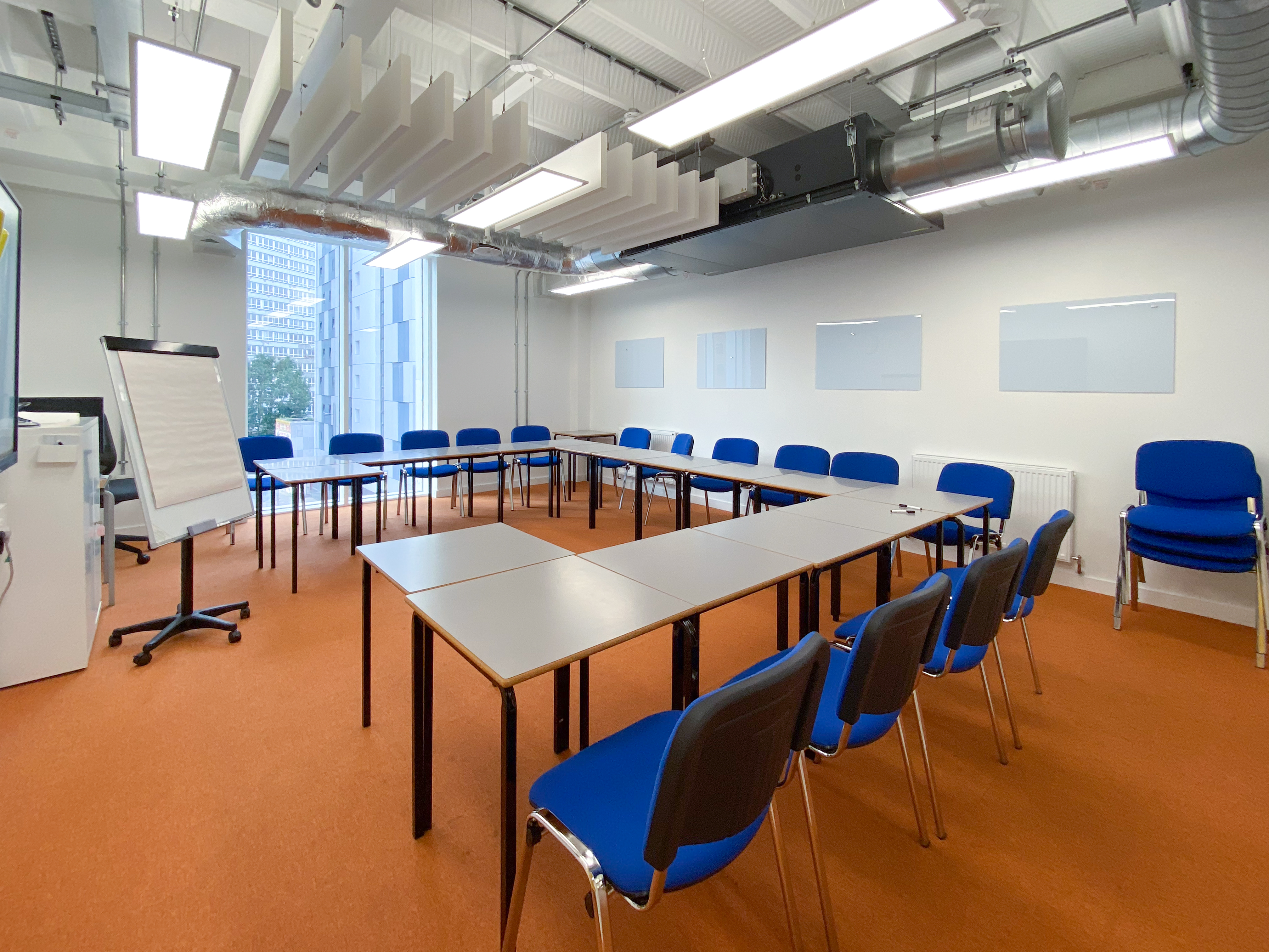 Modern meeting room with blue chairs, ideal for workshops and presentations.