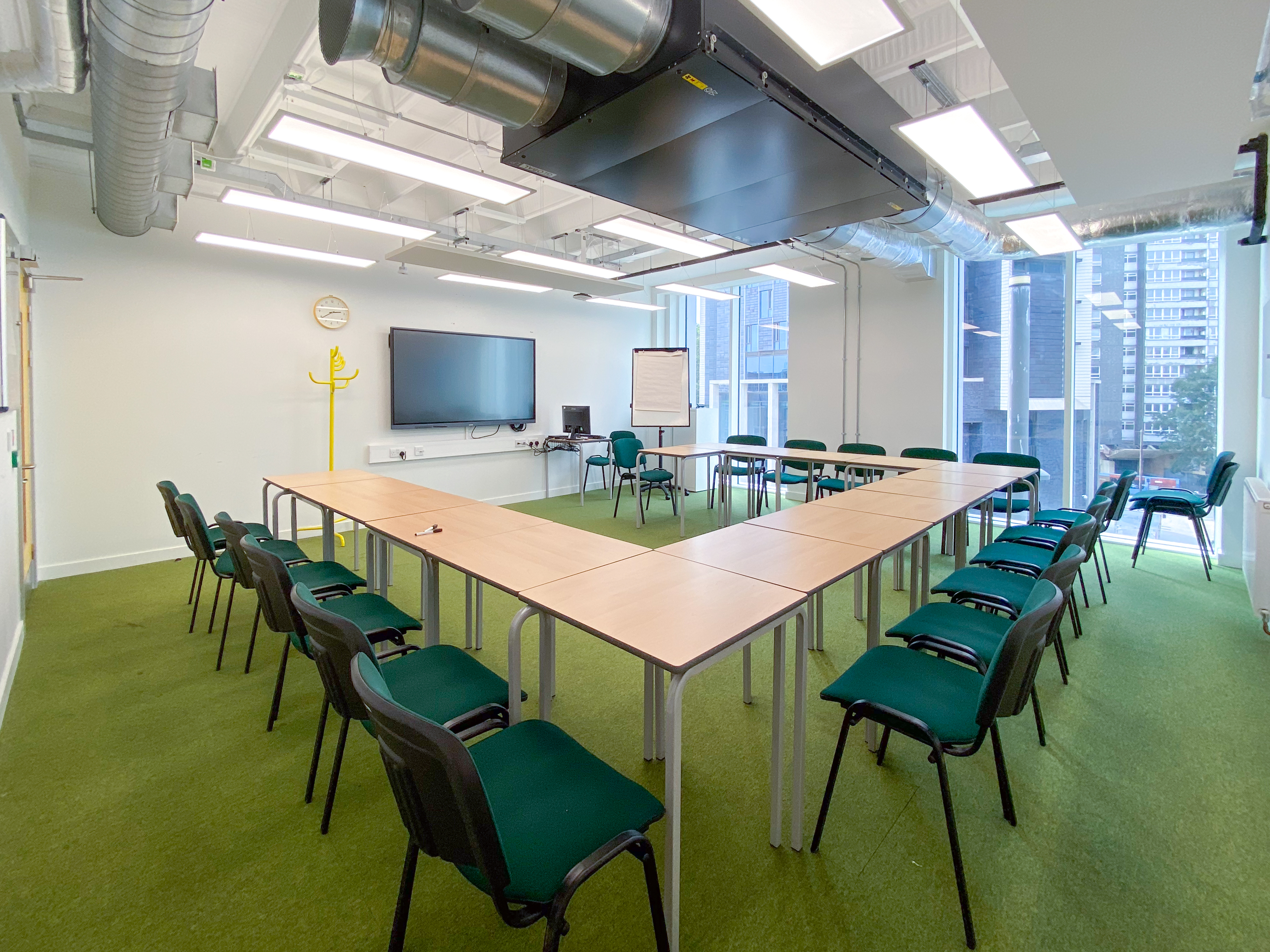 Versatile meeting room with U-shaped seating, ideal for workshops and presentations.