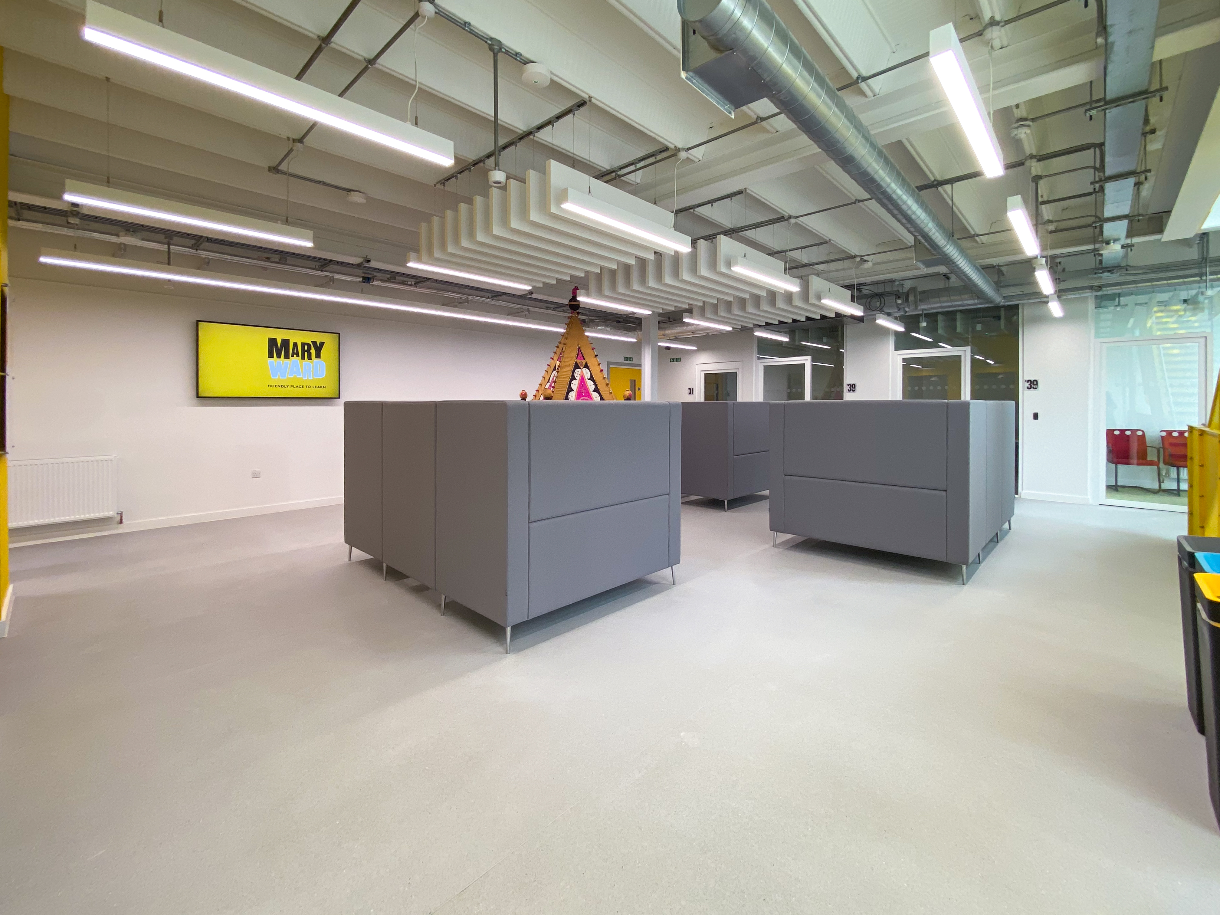 Modern classroom with gray cubicles and yellow accents for collaborative meetings.