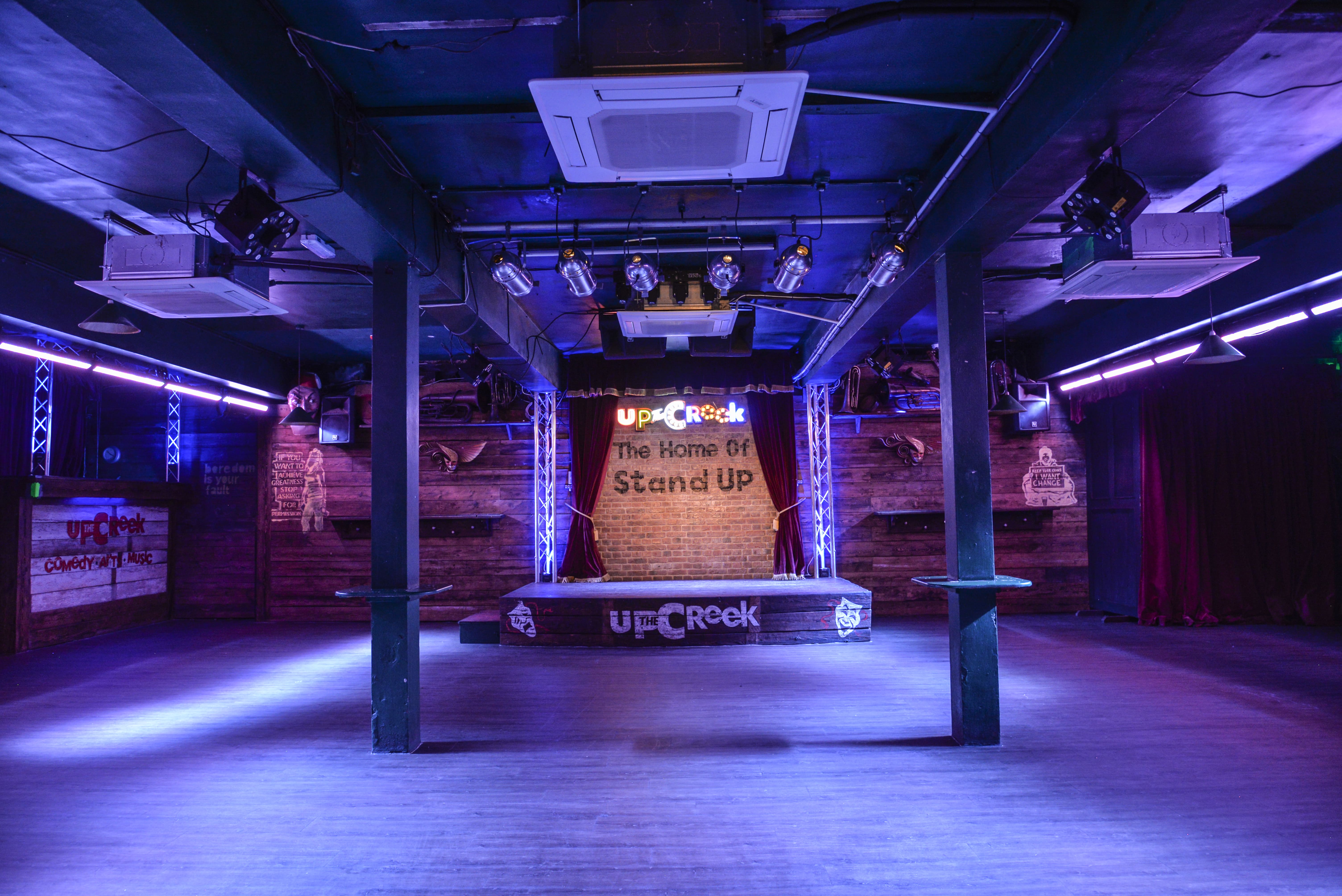 Versatile event space with elevated stage and rustic backdrop for performances or networking.