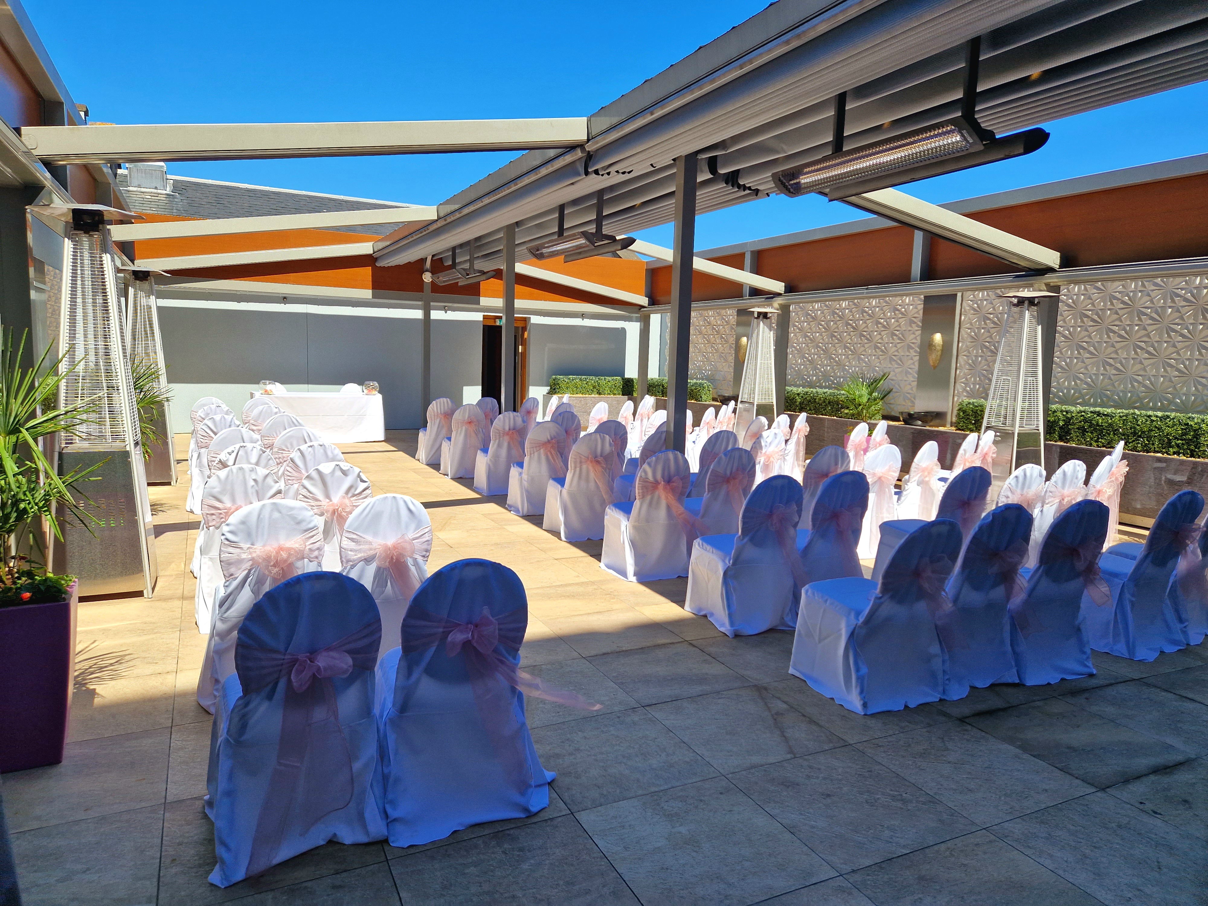 Outdoor wedding venue at The York, featuring elegant chairs with pink sashes.
