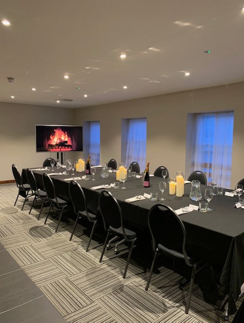 Elegant meeting room at The Baird, featuring a long table and cozy digital fireplace.