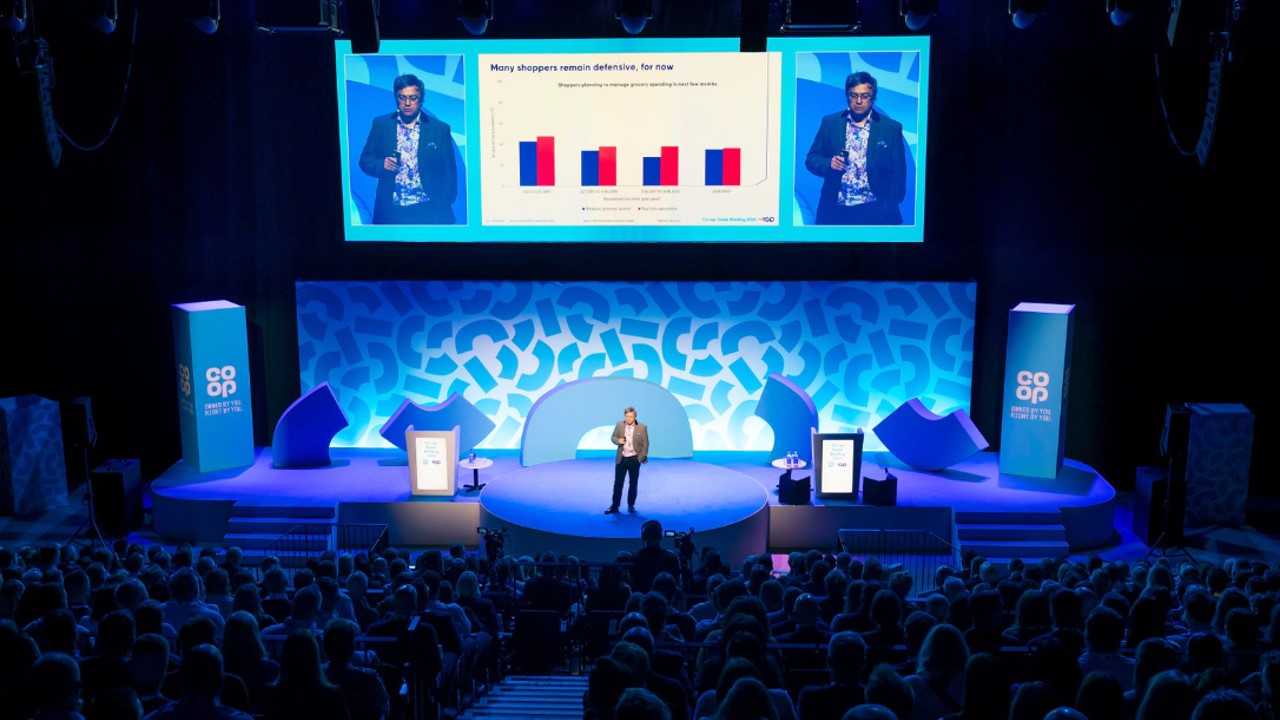 Dynamic conference speaker at The Bowl, Co-op Live: vibrant auditorium with large screens.