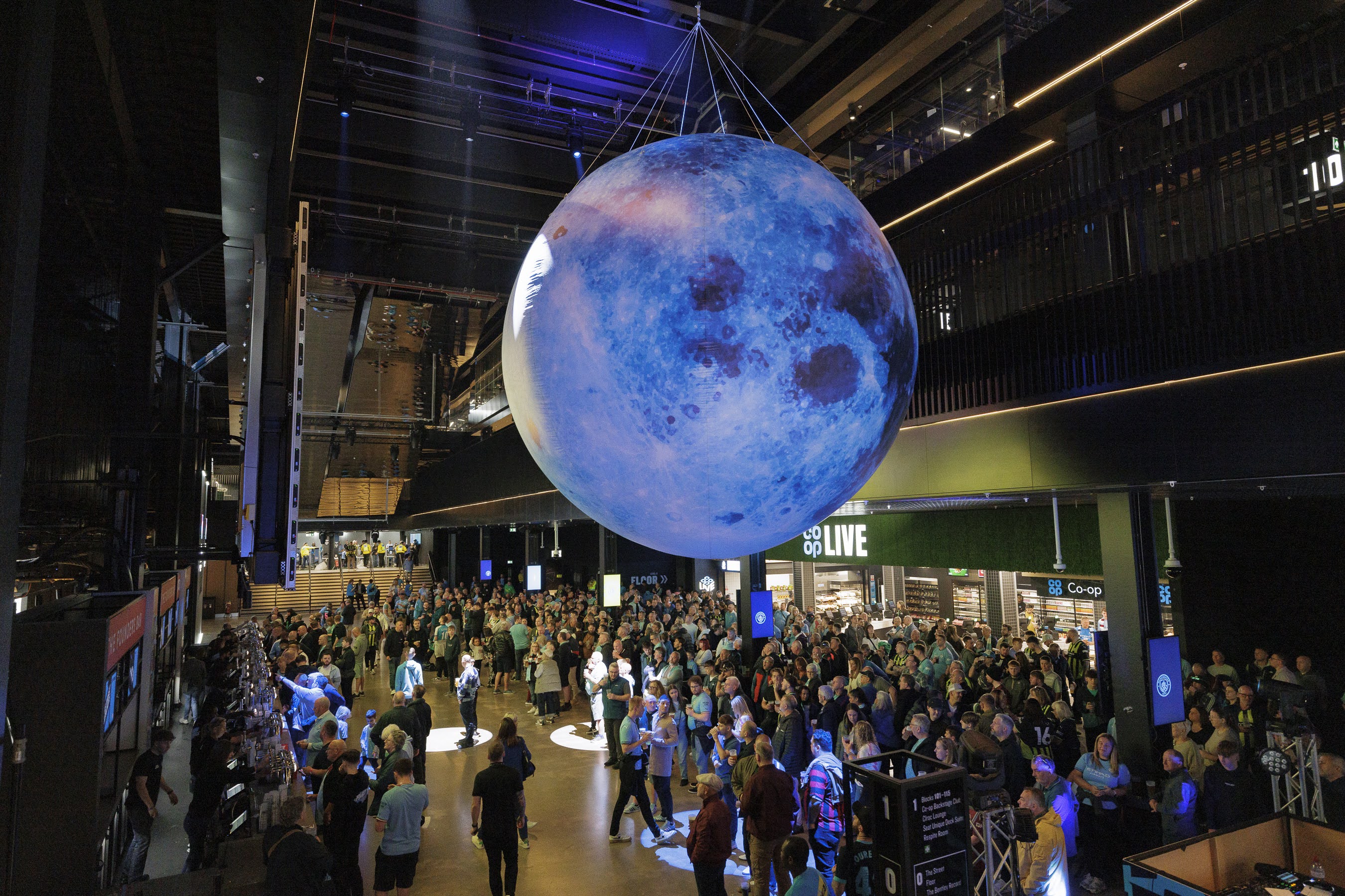 "Vertu Place event space with illuminated moon installation and large crowd gathering."