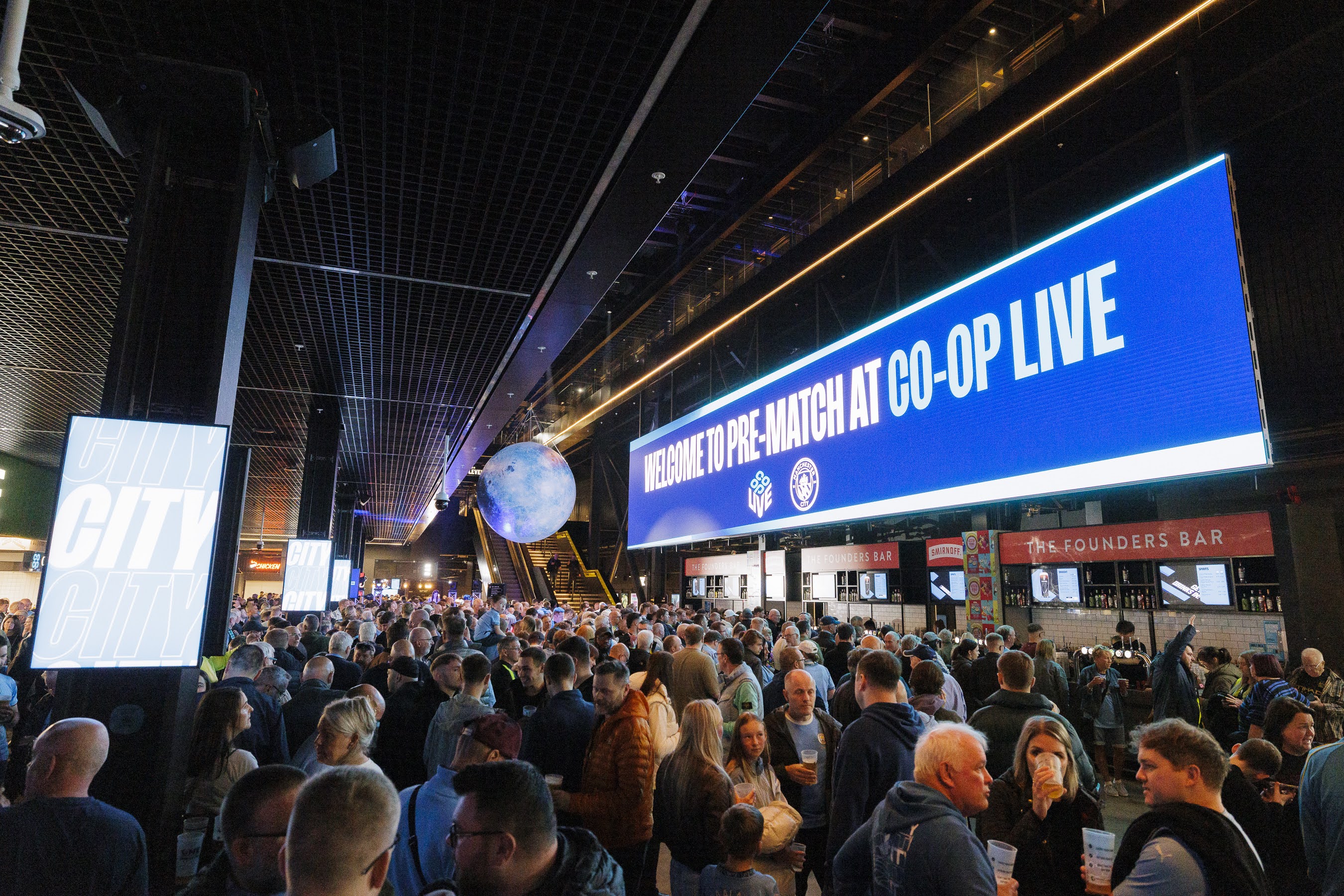 Vibrant event at Vertu Place, Co-op Live; crowd enjoying refreshments and digital signage.
