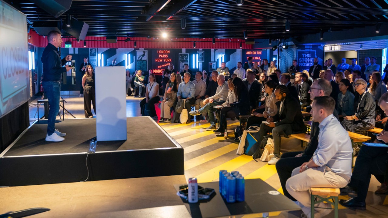 Engaging speaker at Co-op Backstage event in modern venue with focused audience.
