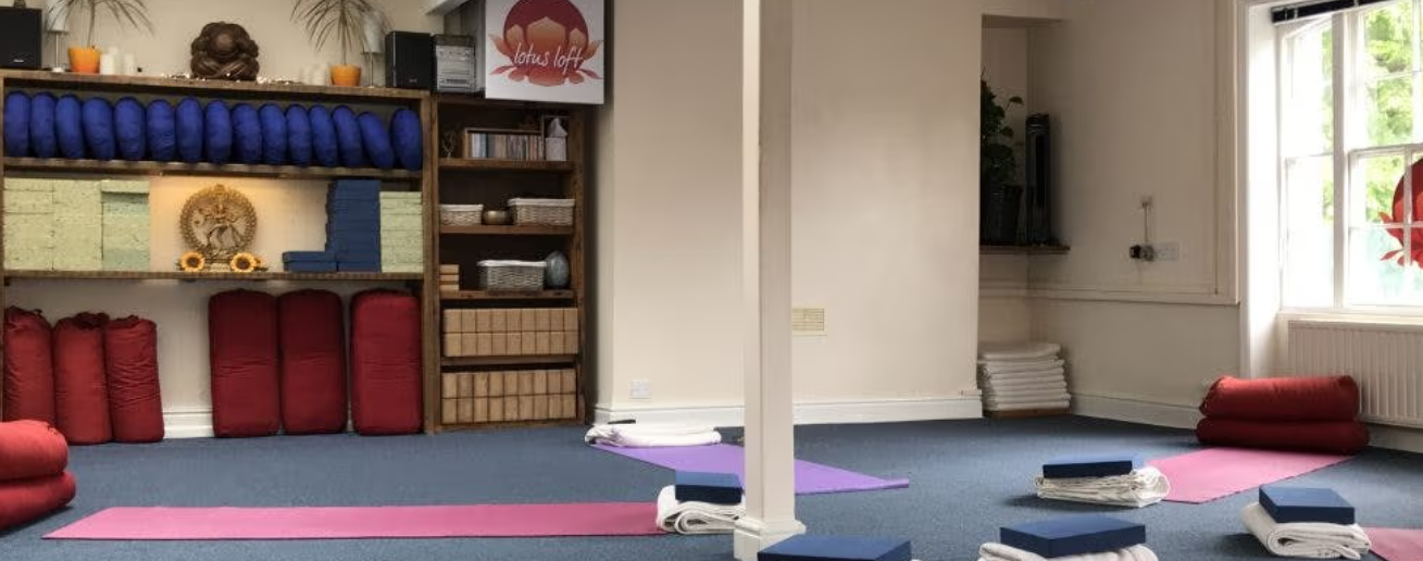 Minimalist yoga studio with prop storage for intimate wellness workshops and somatic therapy sessions.