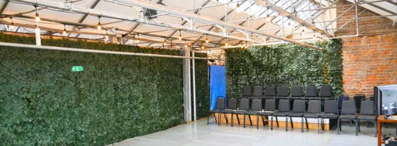 Industrial-chic workshop space with greenery and theater seating for corporate events.