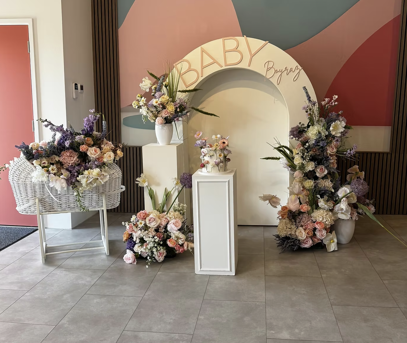 Baby shower event space at Sewardstone Park Suite featuring floral arch backdrop and pedestals.