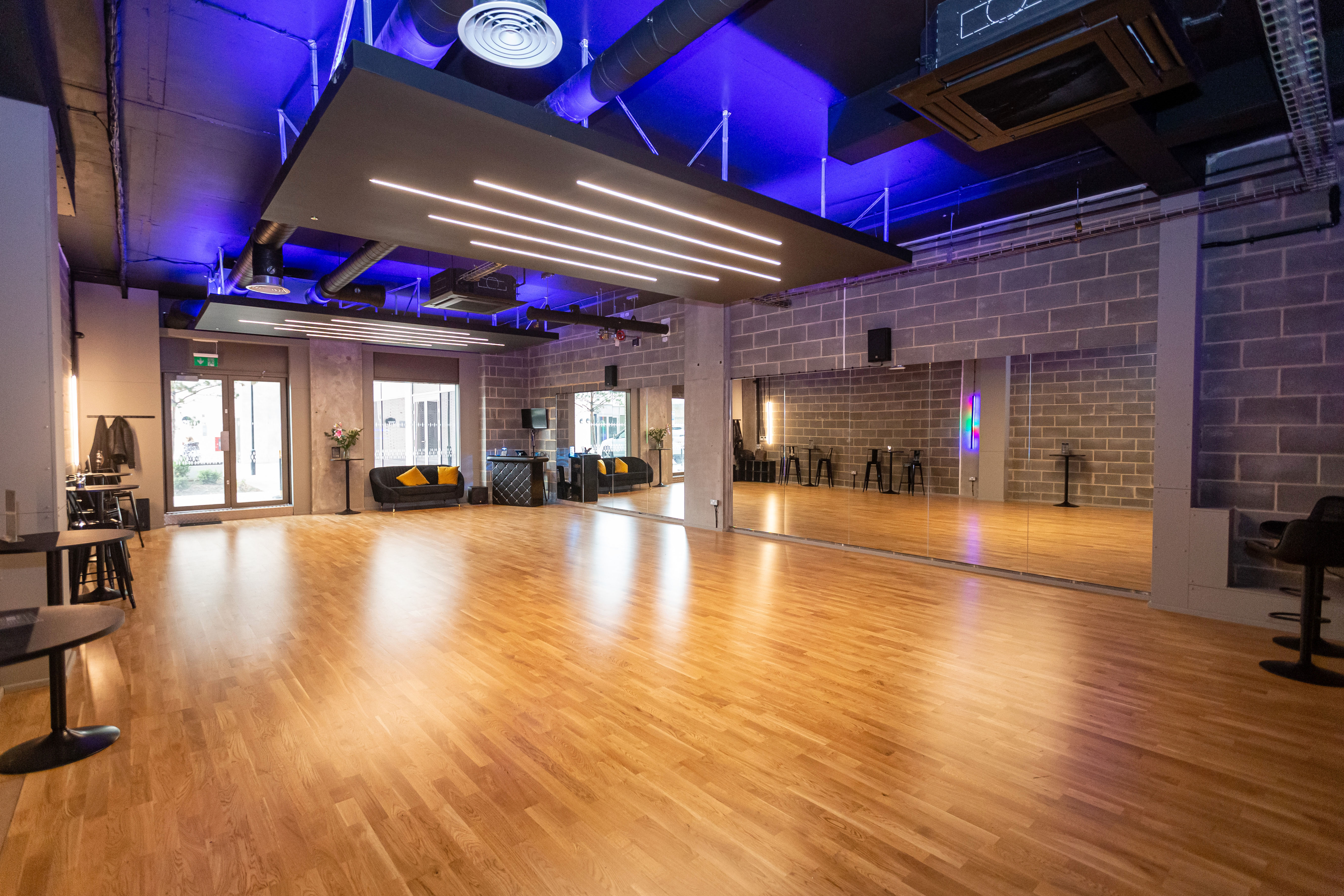 Industrial dance studio with wood floors, ideal for workshops and networking events.
