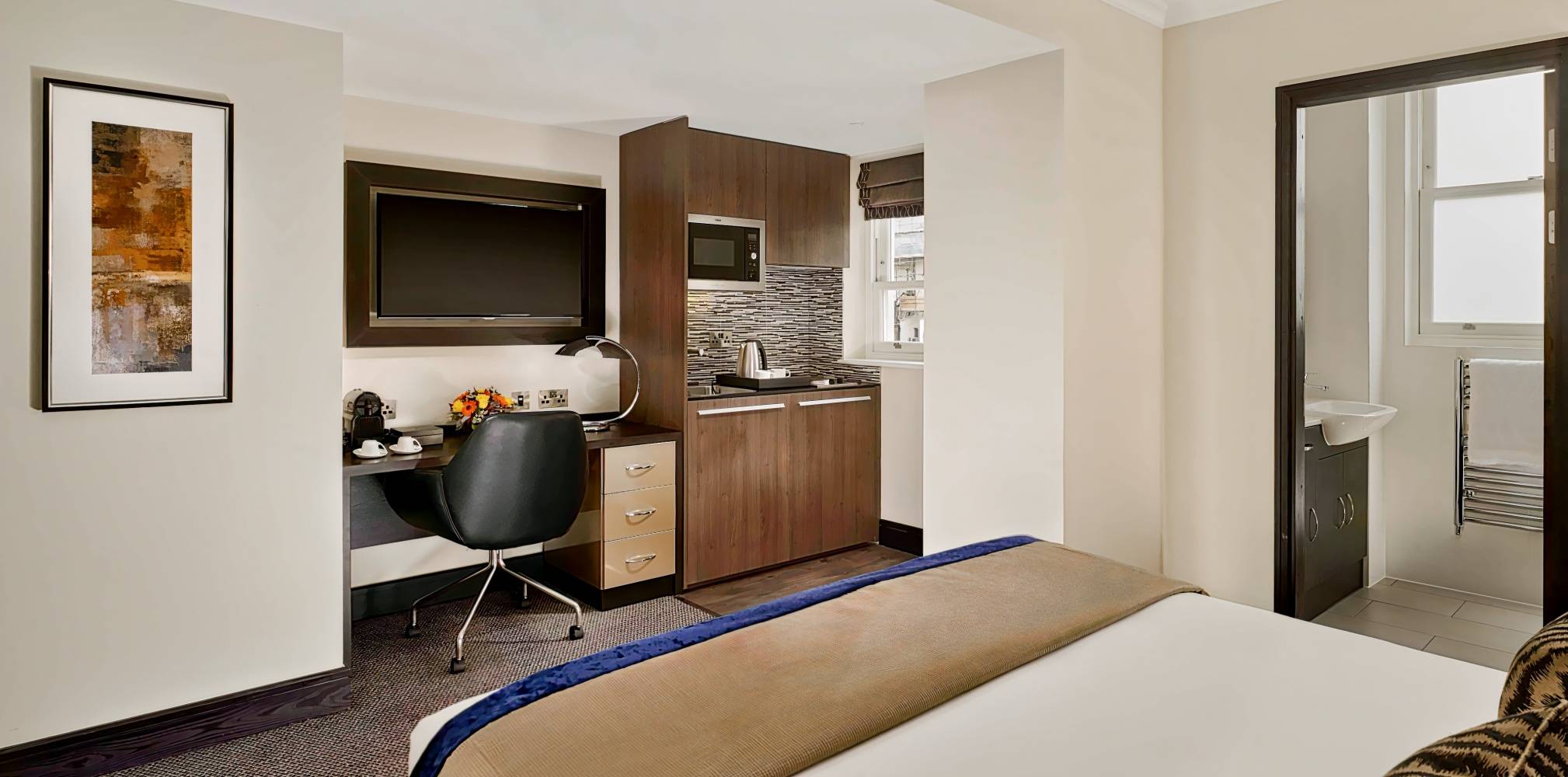 Compact hotel room with kitchenette and workspace at Westbourne Hyde Park for business travel.