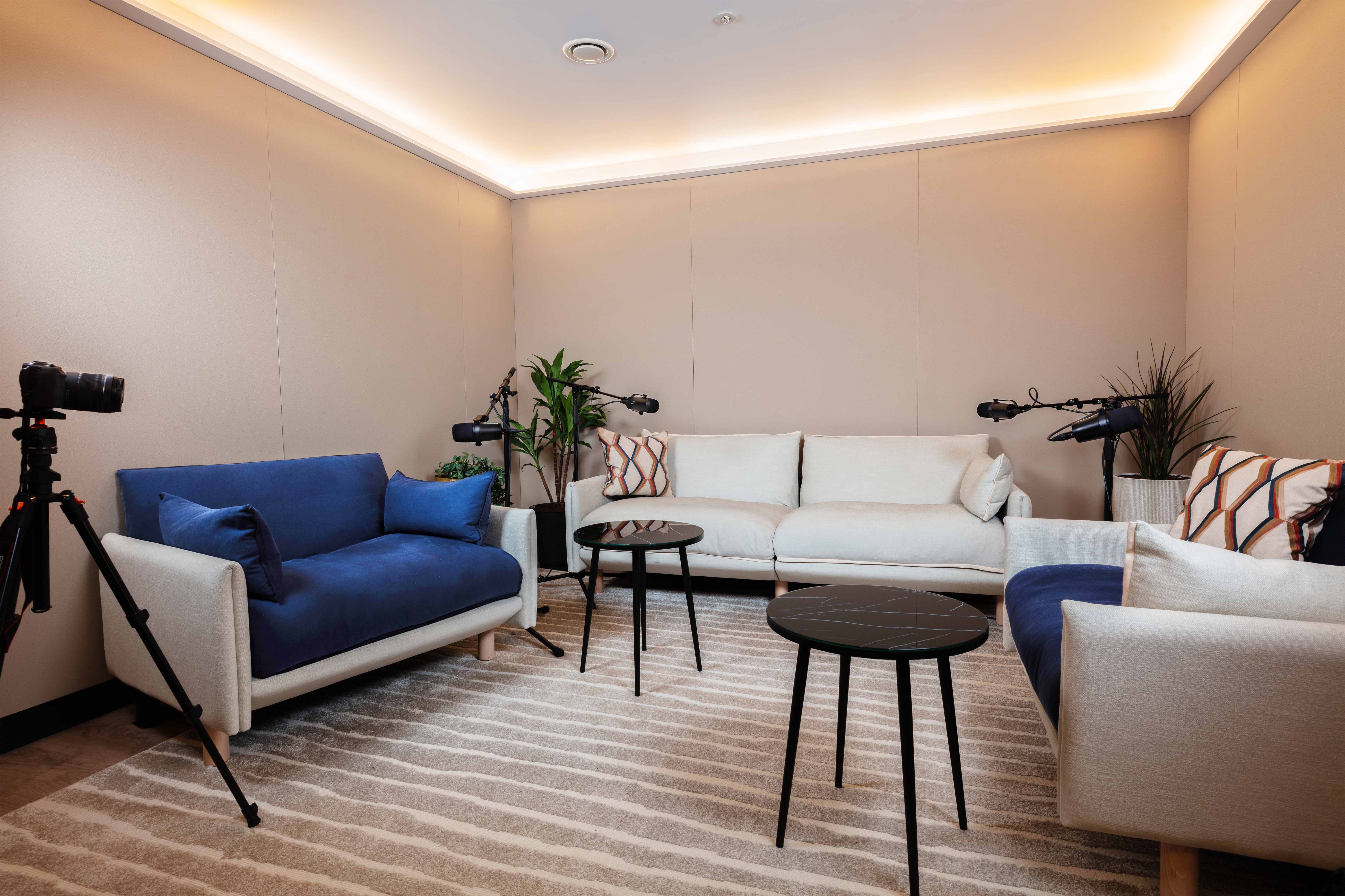 Modern podcast studio with comfy seating, ideal for intimate recordings and presentations.
