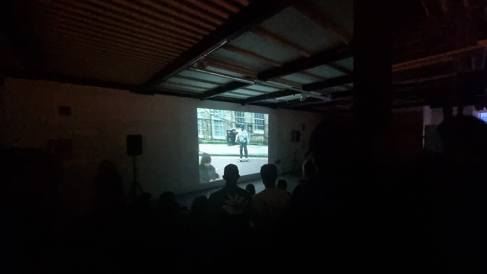 Stryx art gallery event: poorly lit industrial screening space with AV setup.