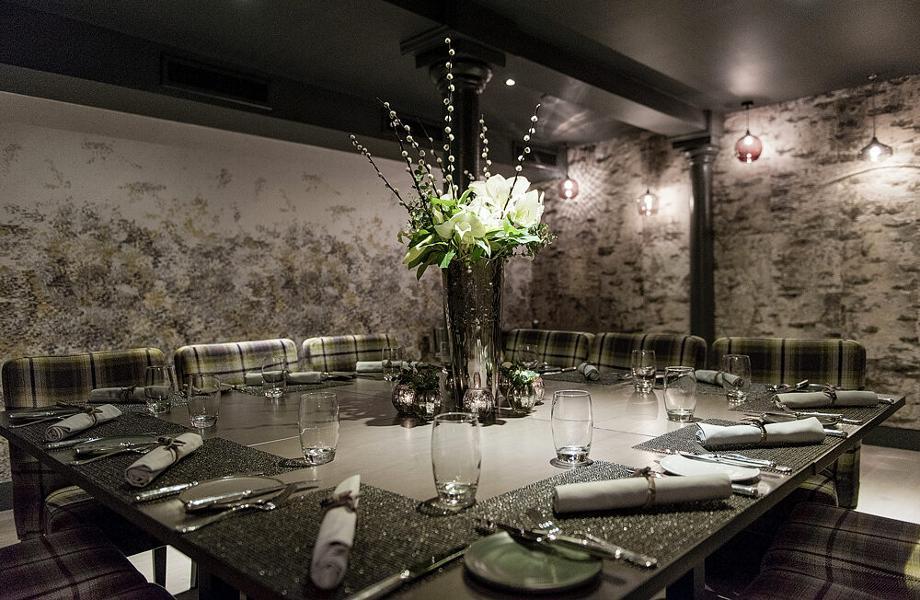 Intimate private dining at The Kitchin featuring textured stone walls for luxury event venue hire.