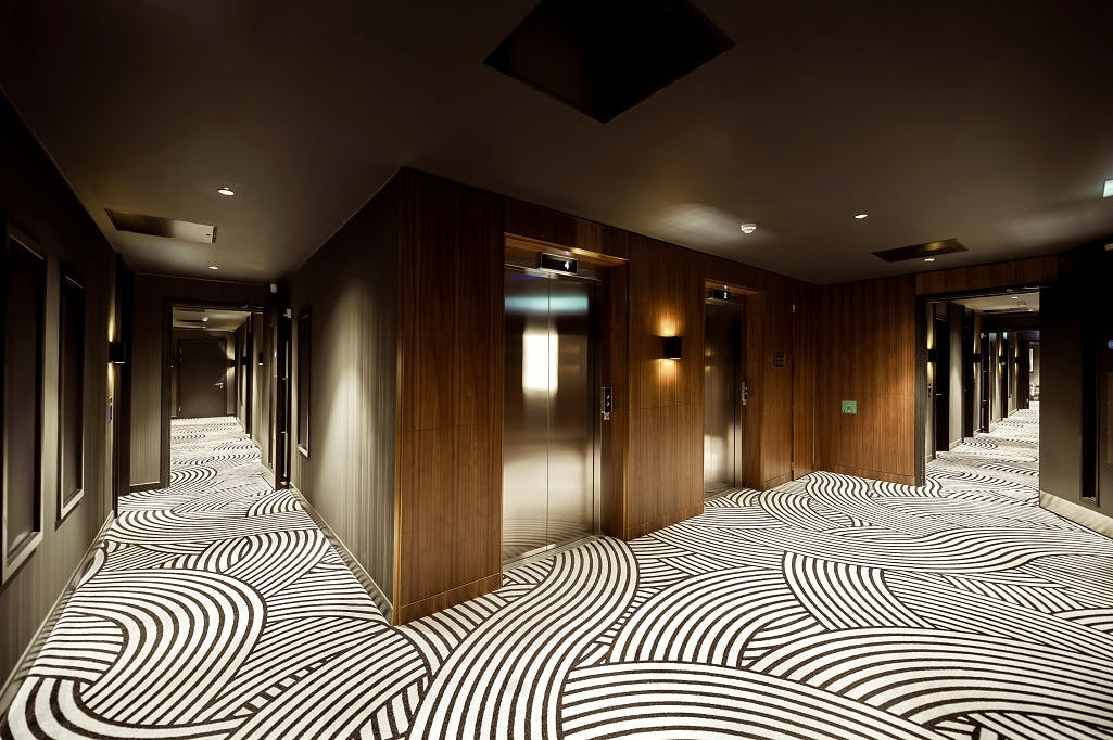 Modern hotel lift lobby with wood paneling, ideal for event wayfinding and brand signage.