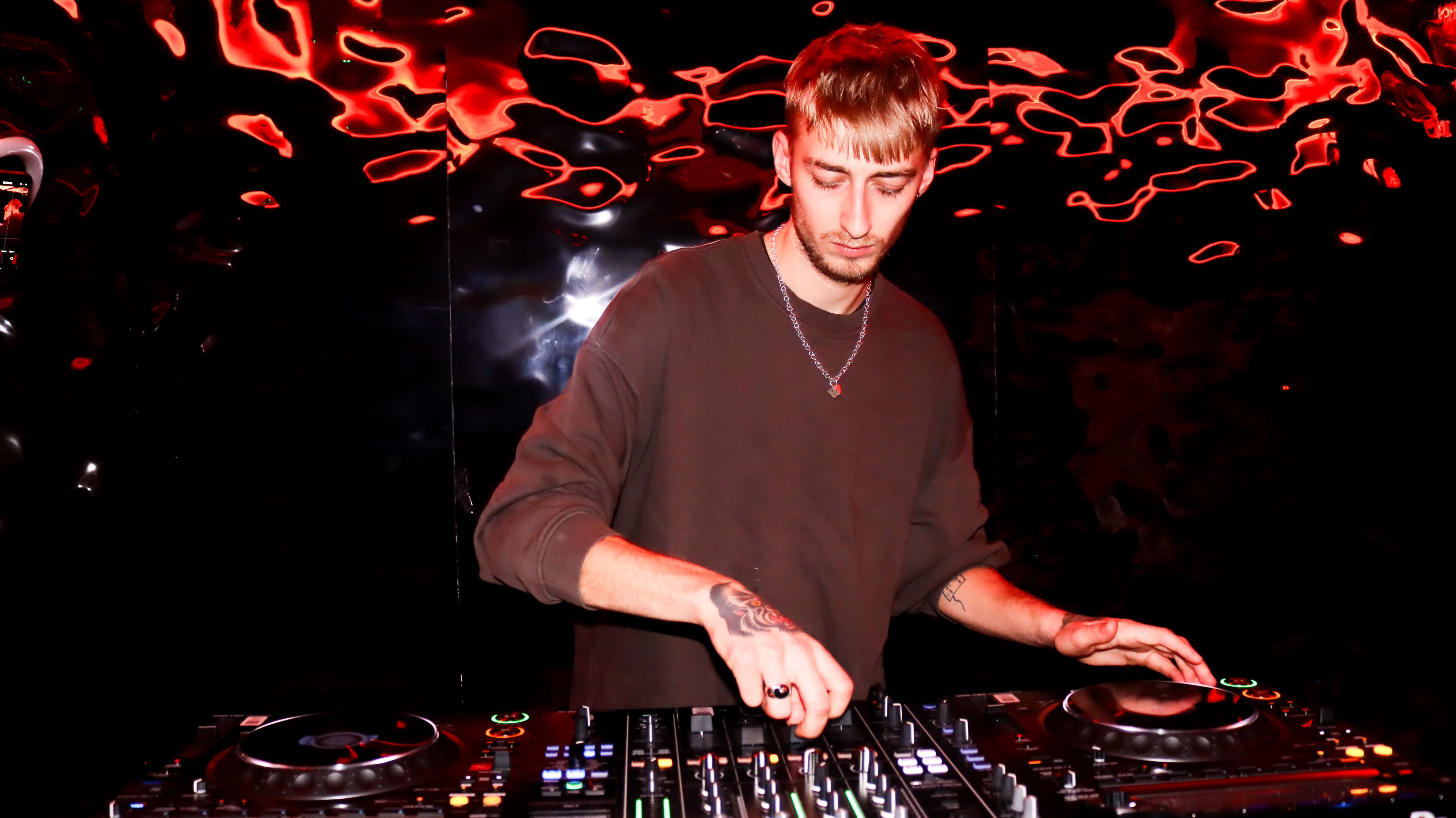 DJ performing at vibrant SE London event with dynamic lighting and sound setup.