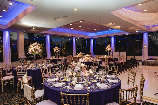 Ballroom setup at Jacaranda Club with purple lighting and gold chairs for corporate gala events.