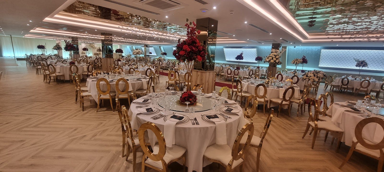Royal Nawaab banquet hall with gold chairs and red floral centerpieces for wedding event venue.