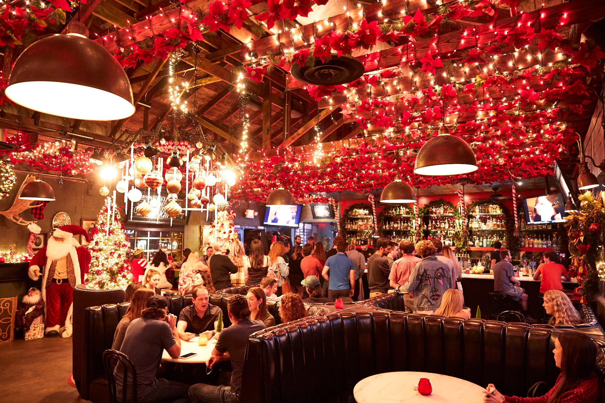 Festive holiday pop-up bar with ceiling florals and string lighting for event venue rental.