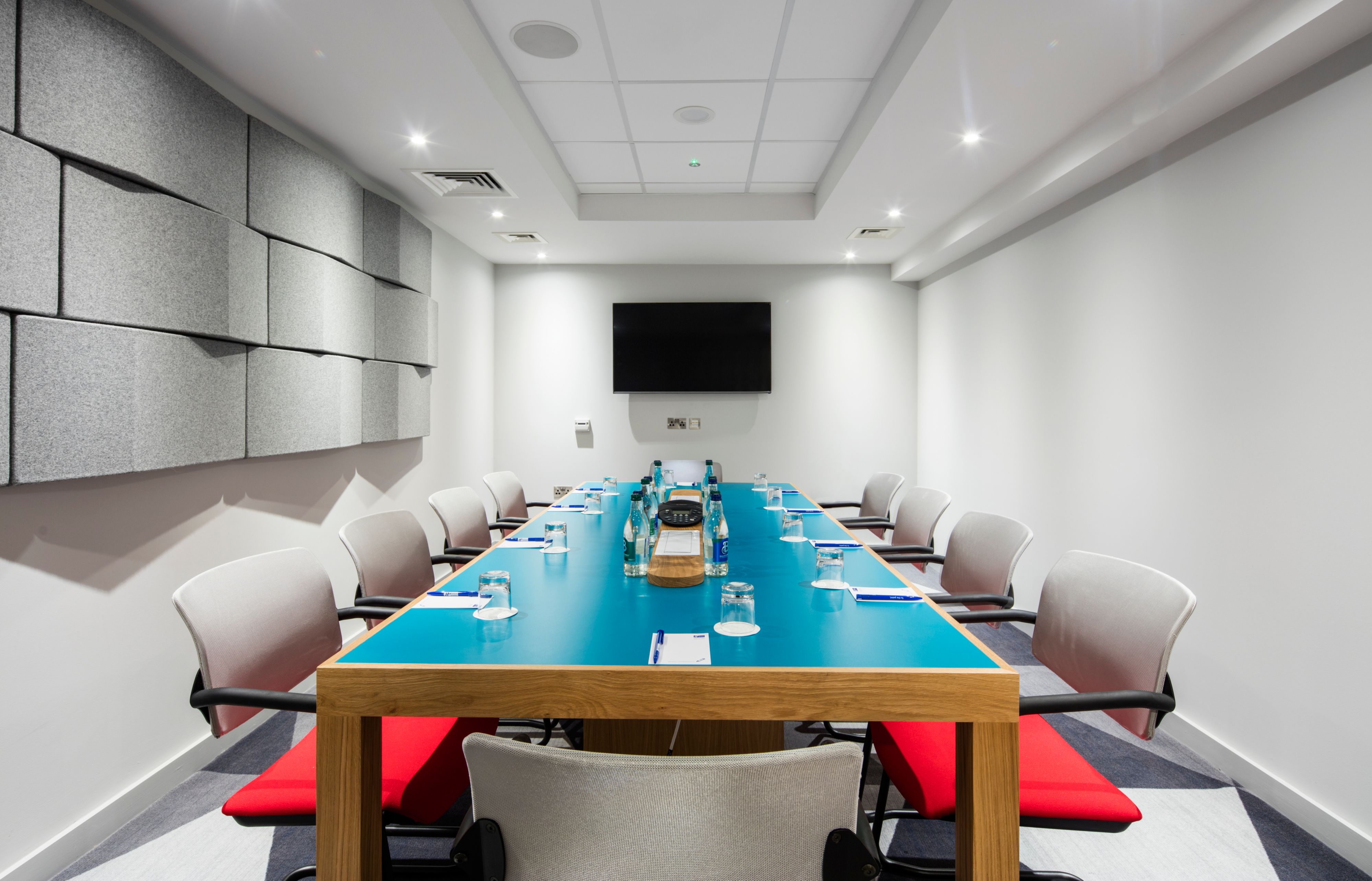 Boardroom-style conference room with blue table for professional corporate meetings and events.