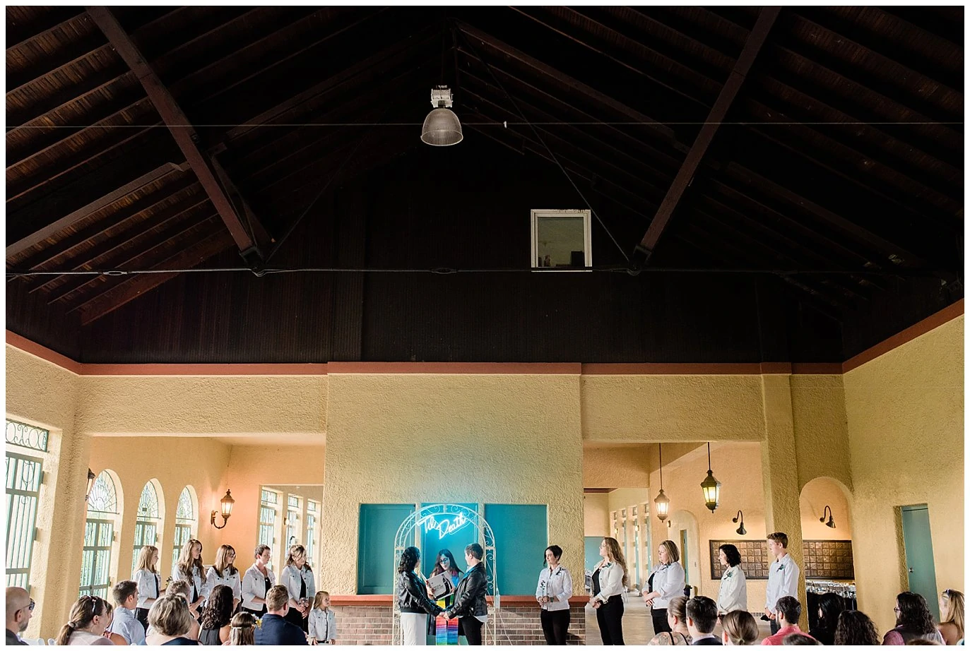 Intimate ceremony at City Park Pavilion featuring high ceilings and modern neon wedding decor.