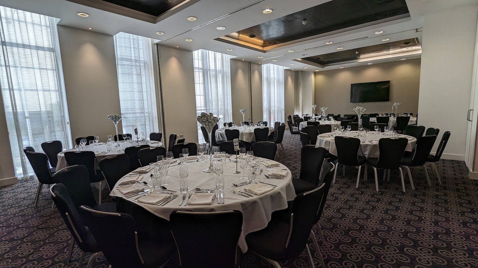 Elegant event space at Radisson Blu Cardiff with round tables and natural light.