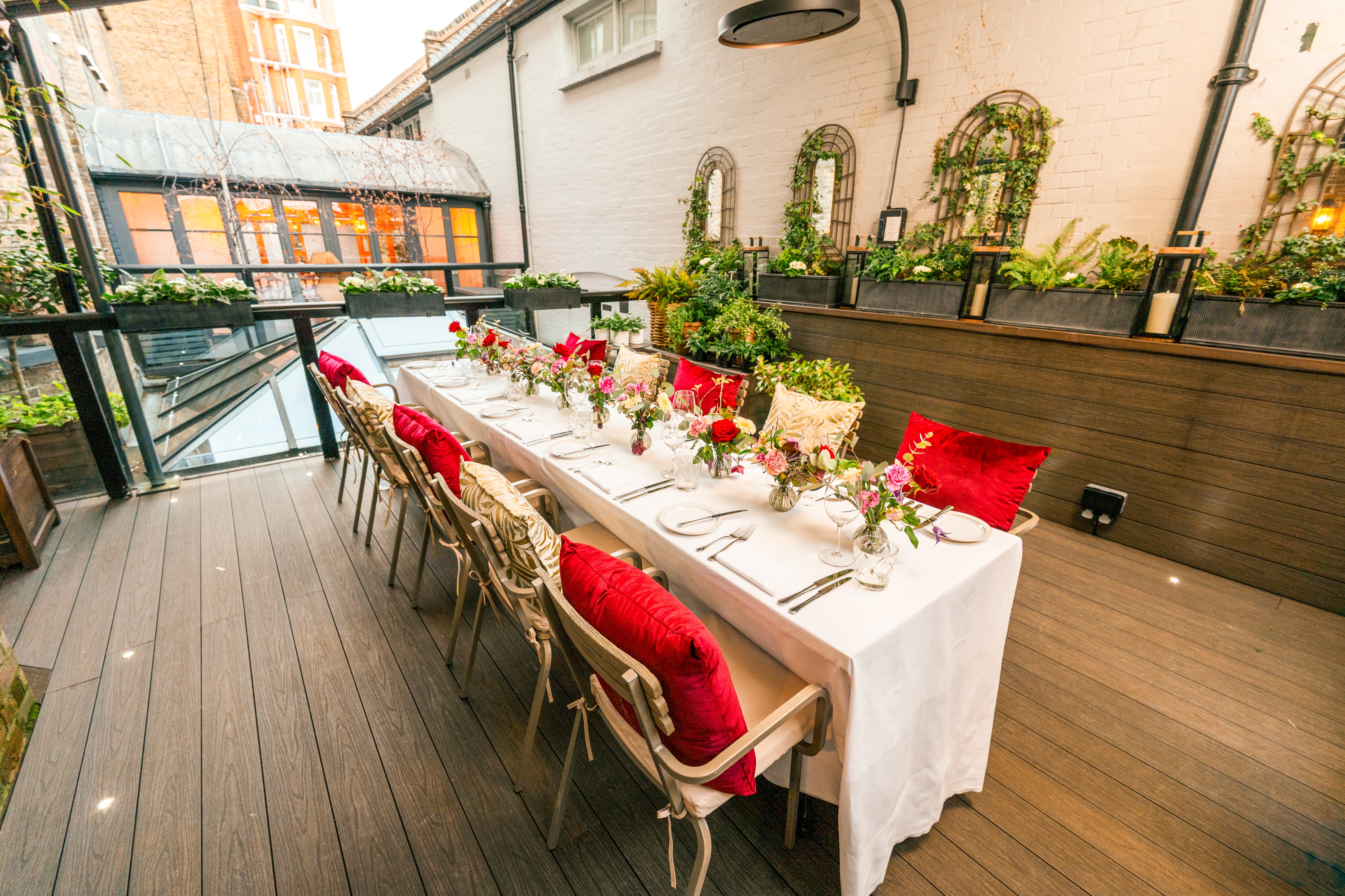 Private luncheon in The Secret Garden with red velvet cushions and floral decor for boutique events.