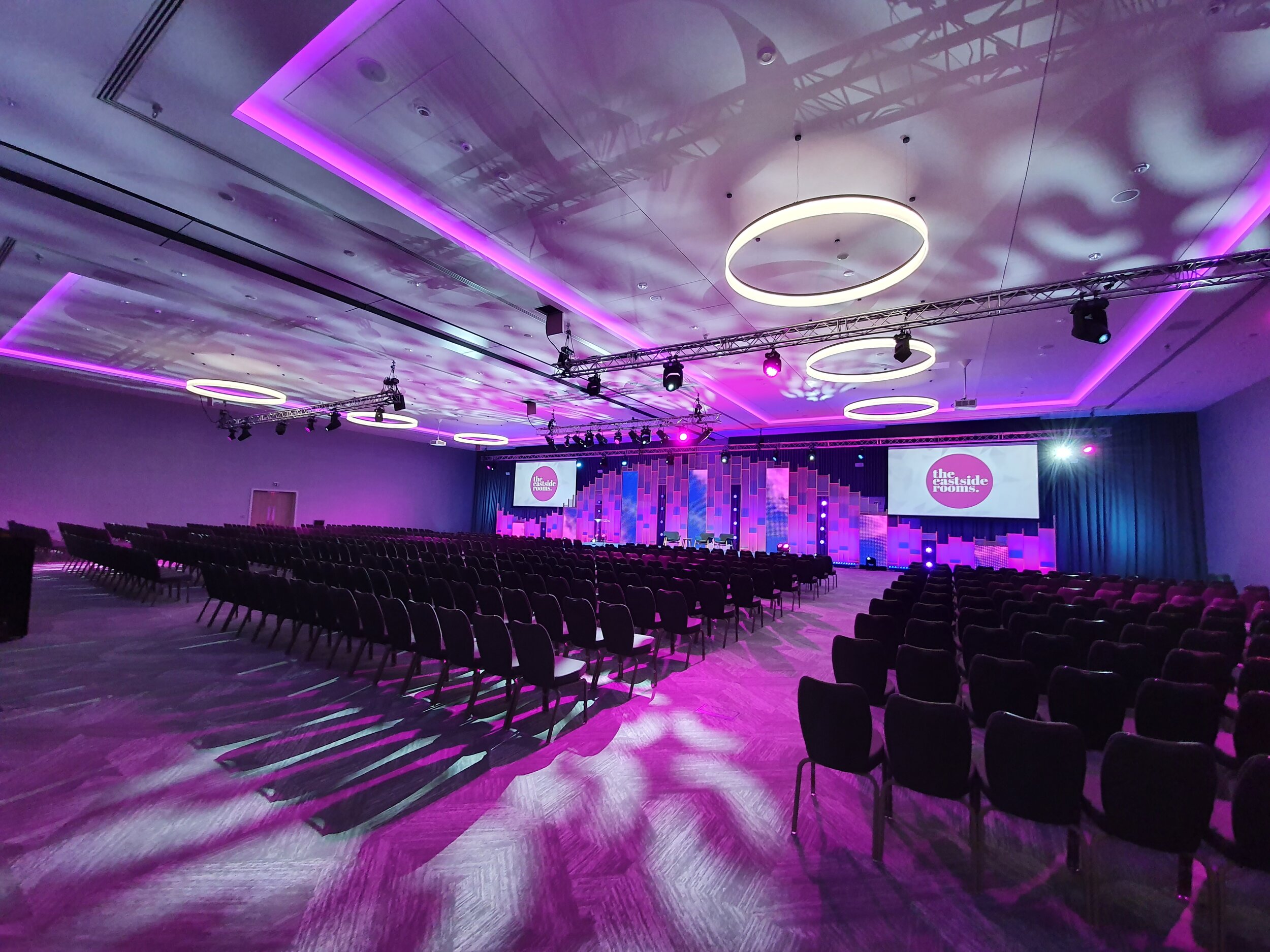 Theater-style conference room at Aloft Birmingham Eastside with purple lighting and AV setup.