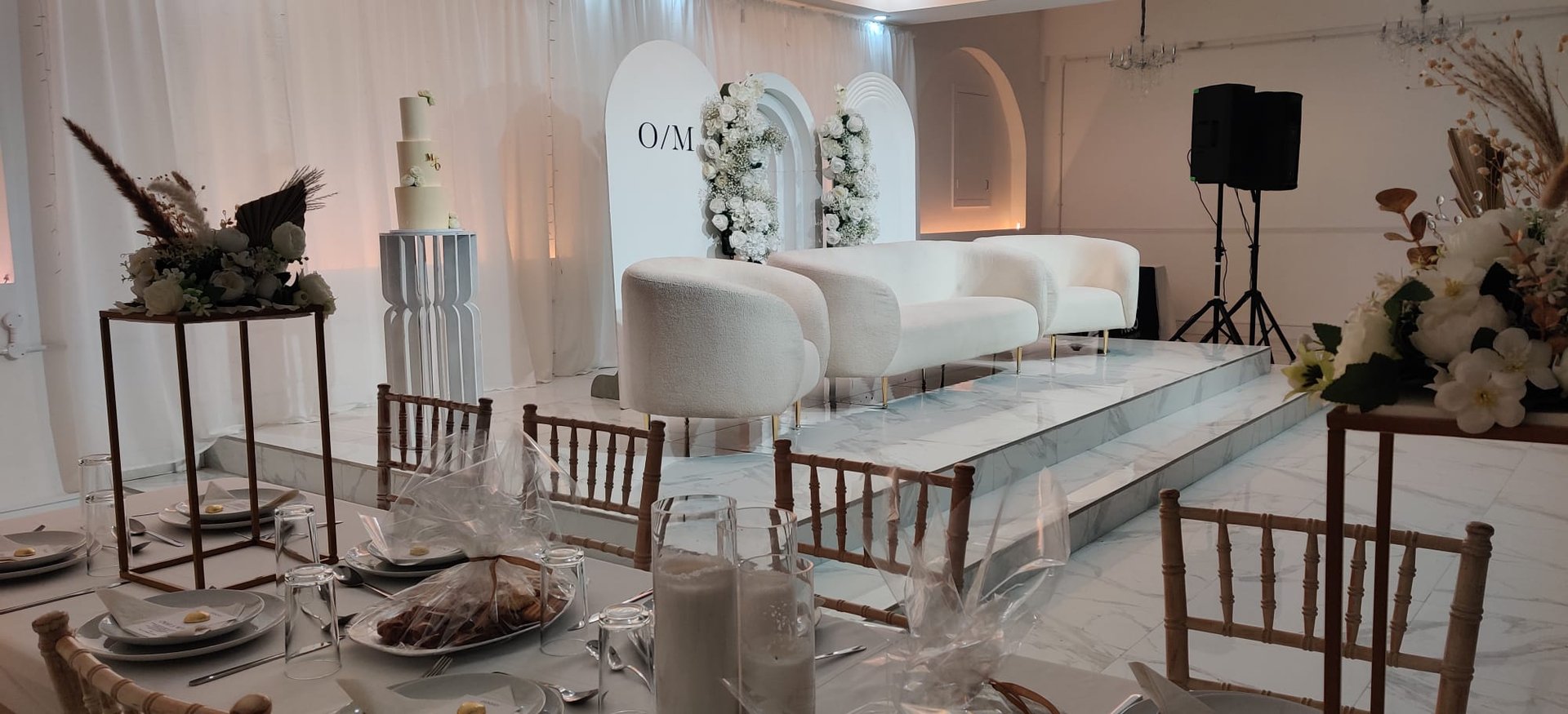 Modern sweetheart stage with arched backdrop for bridal event or luxury wedding venue.